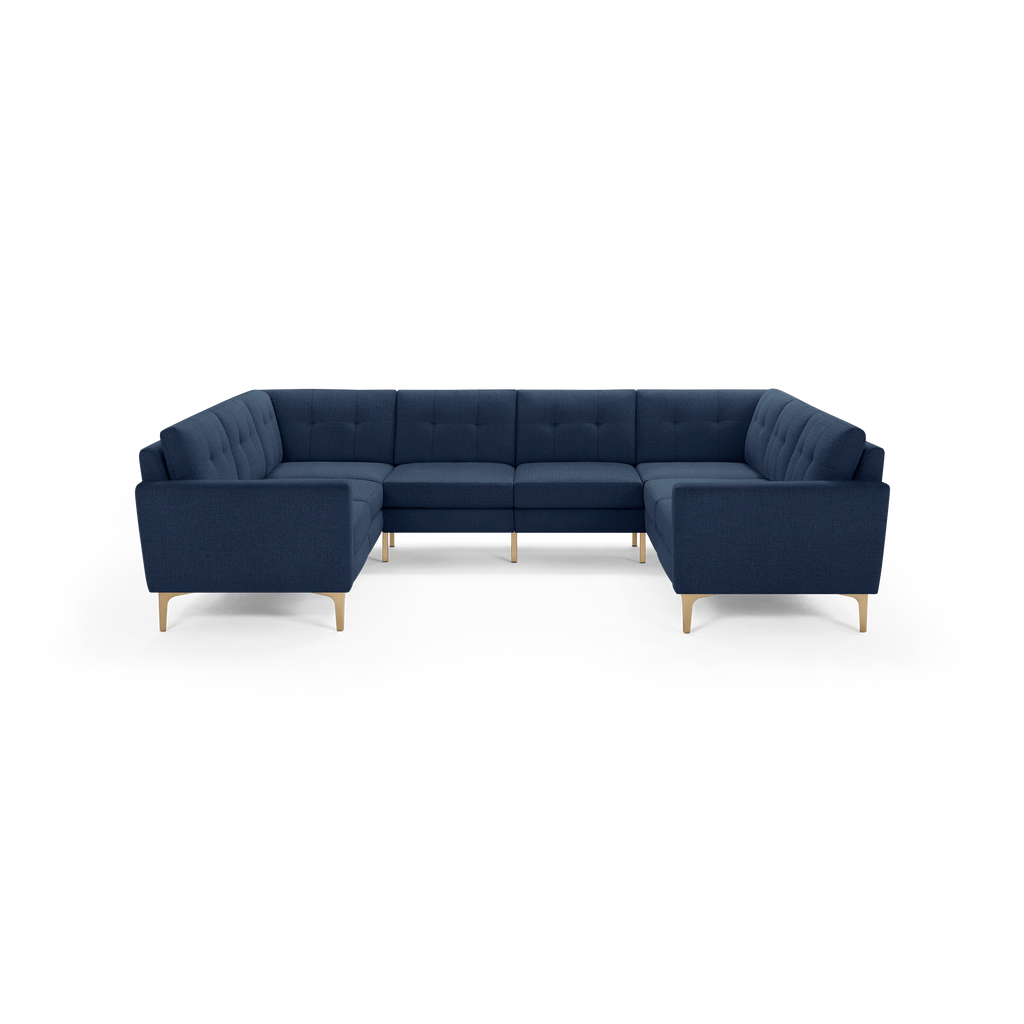 Large U-shaped sectional sofa with deep blue fabric upholstery, tufted cushions, and light wooden legs.