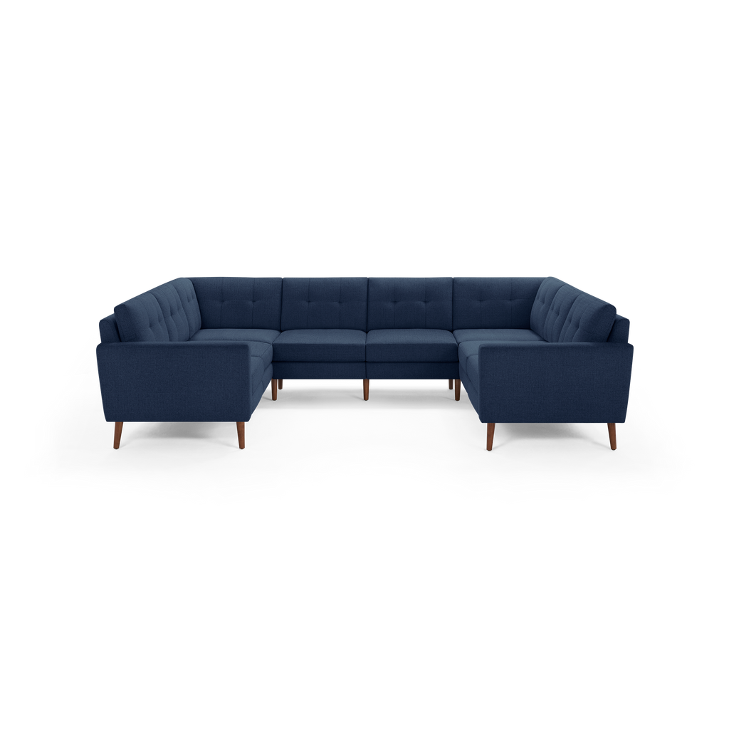 Large U-shaped sectional sofa with deep blue fabric upholstery, tufted back cushions, and wooden tapered legs.