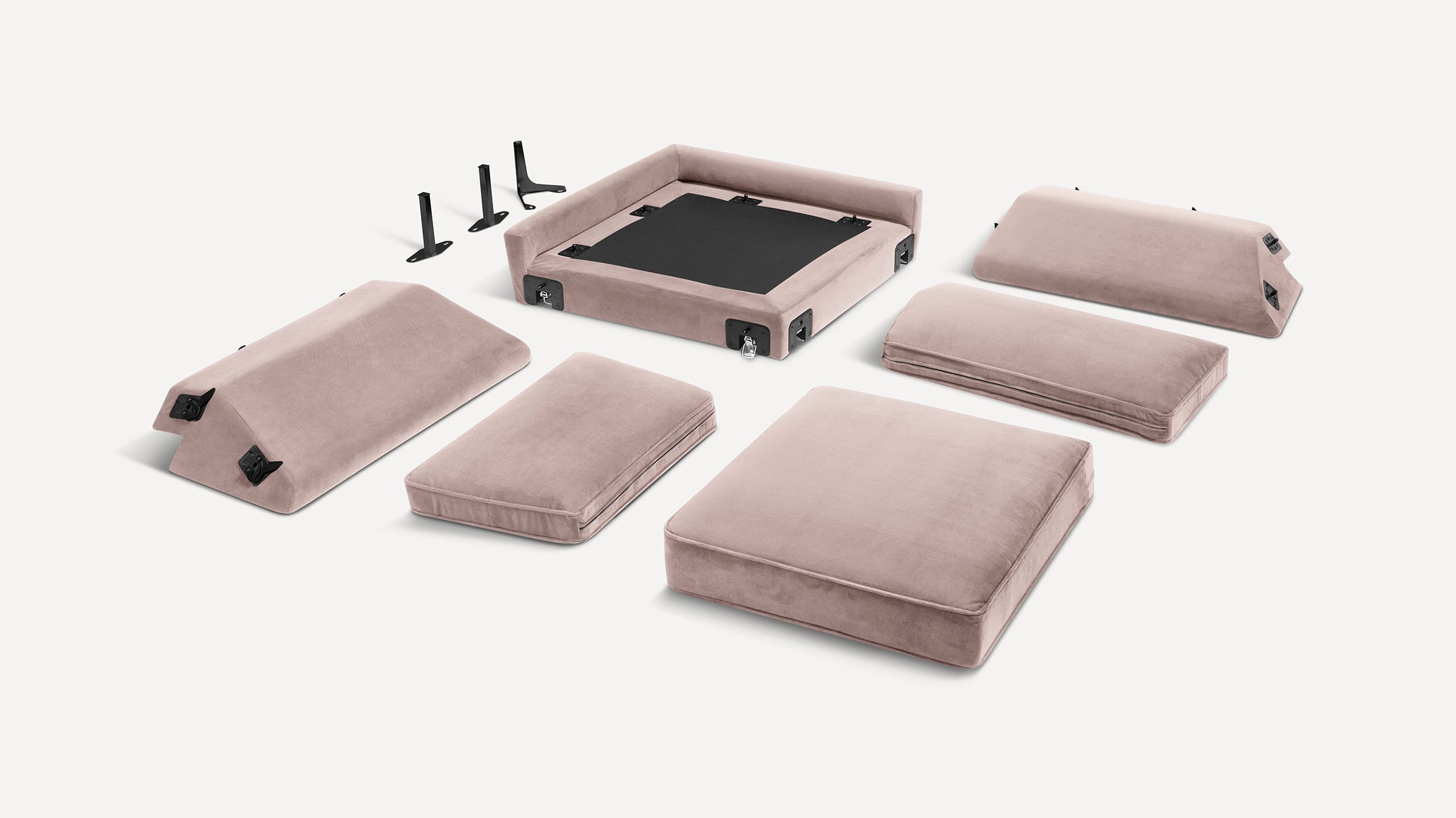 Disassembled soft pink velvet modular sofa cushions, backrests, base frame, and four black metal support legs on white background.