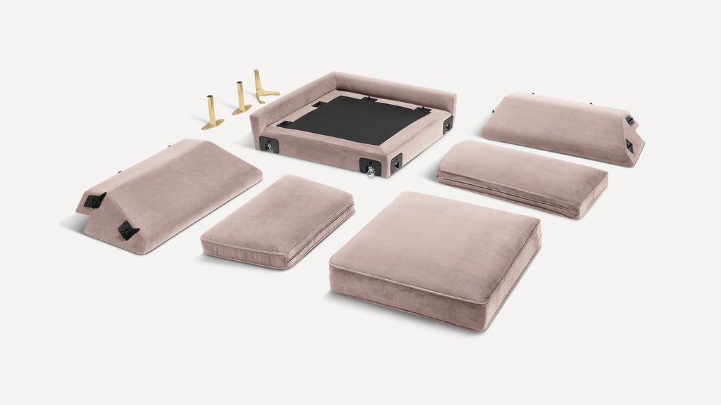 Disassembled modern pink velvet cushioned sofa pieces with gold metal legs, displayed on a white background.