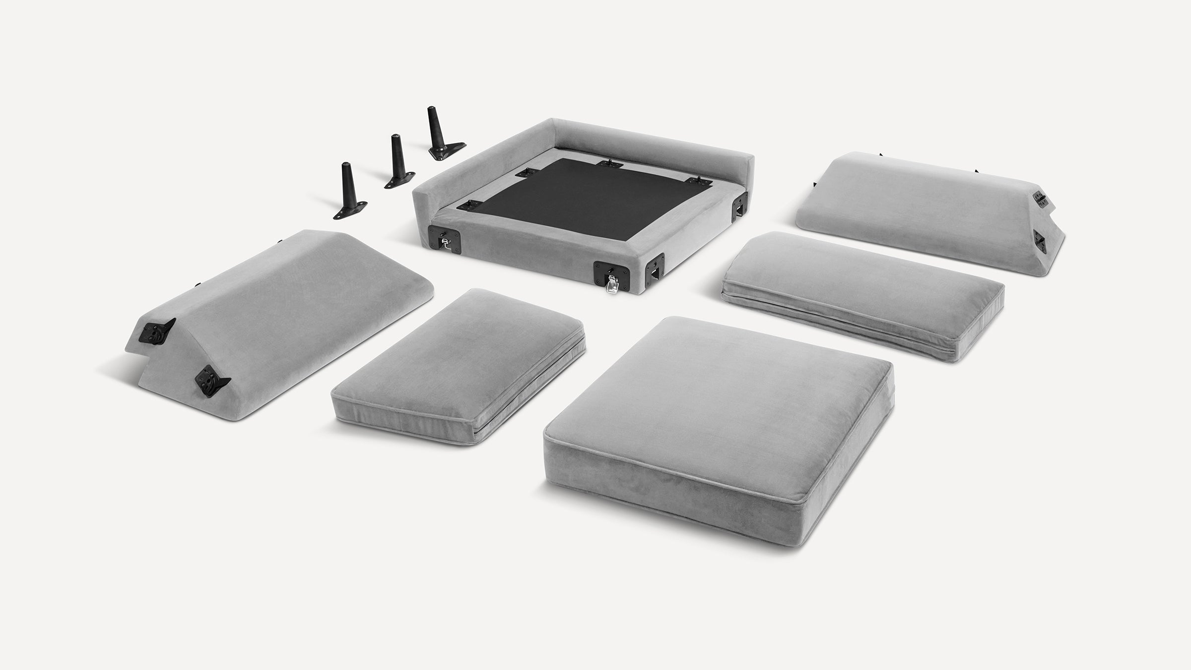 Disassembled light gray modular sofa with cushions, armrests, base frame, and four black metal legs on a white background.