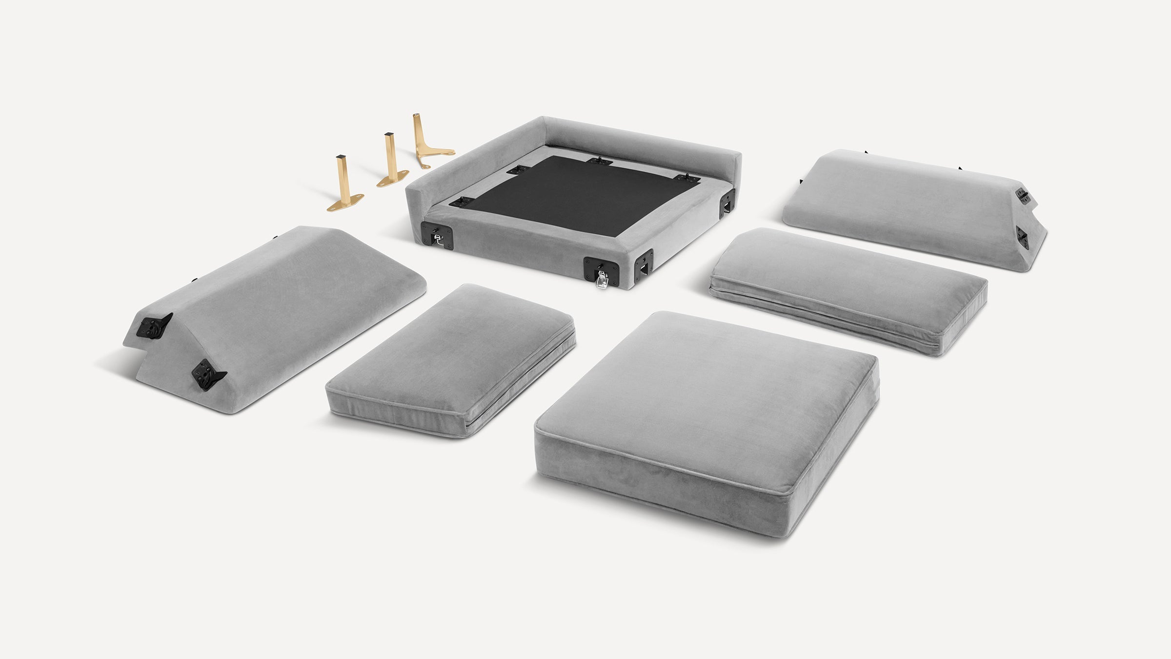Disassembled light gray modular sofa cushions and backrests with metal hardware and four gold-colored legs on a white background.