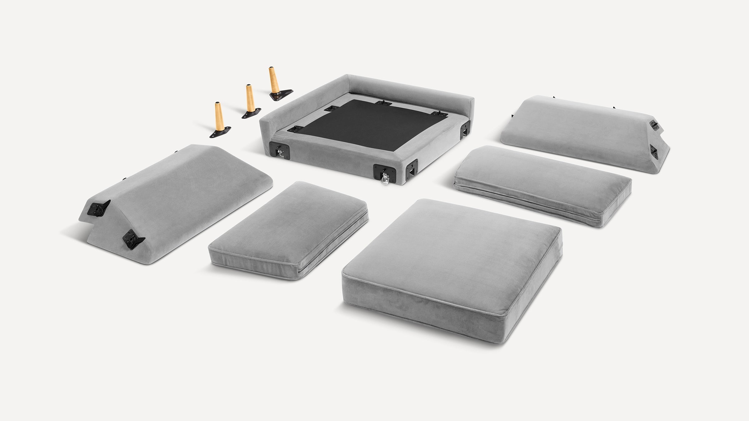 Disassembled modern gray velvet sofa with cushions, backrests, base frame, and four tapered wooden legs displayed on white background.