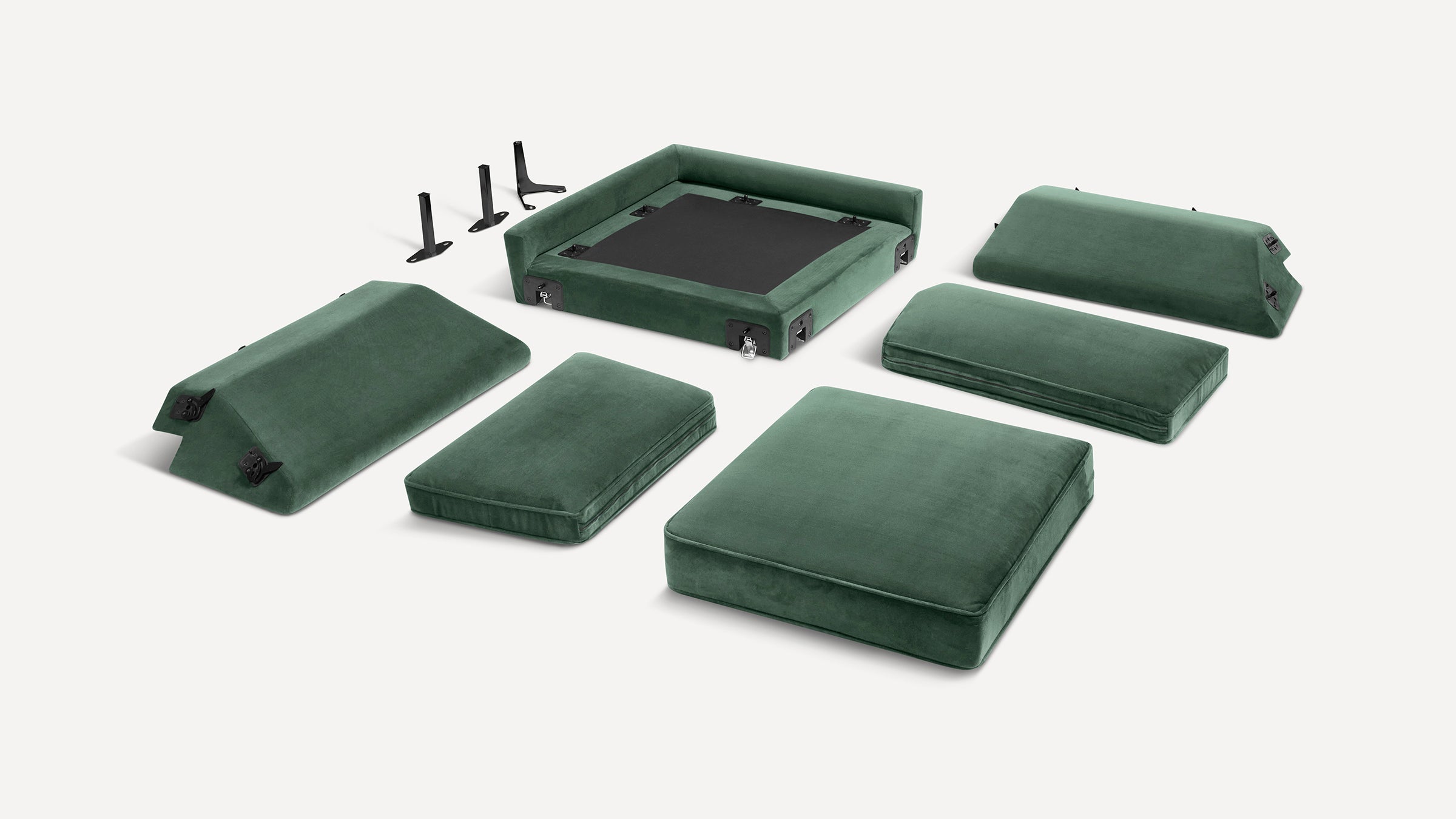 Disassembled green velvet sofa cushions and frame parts, including seating, backrests, and black metal support legs on a white background.