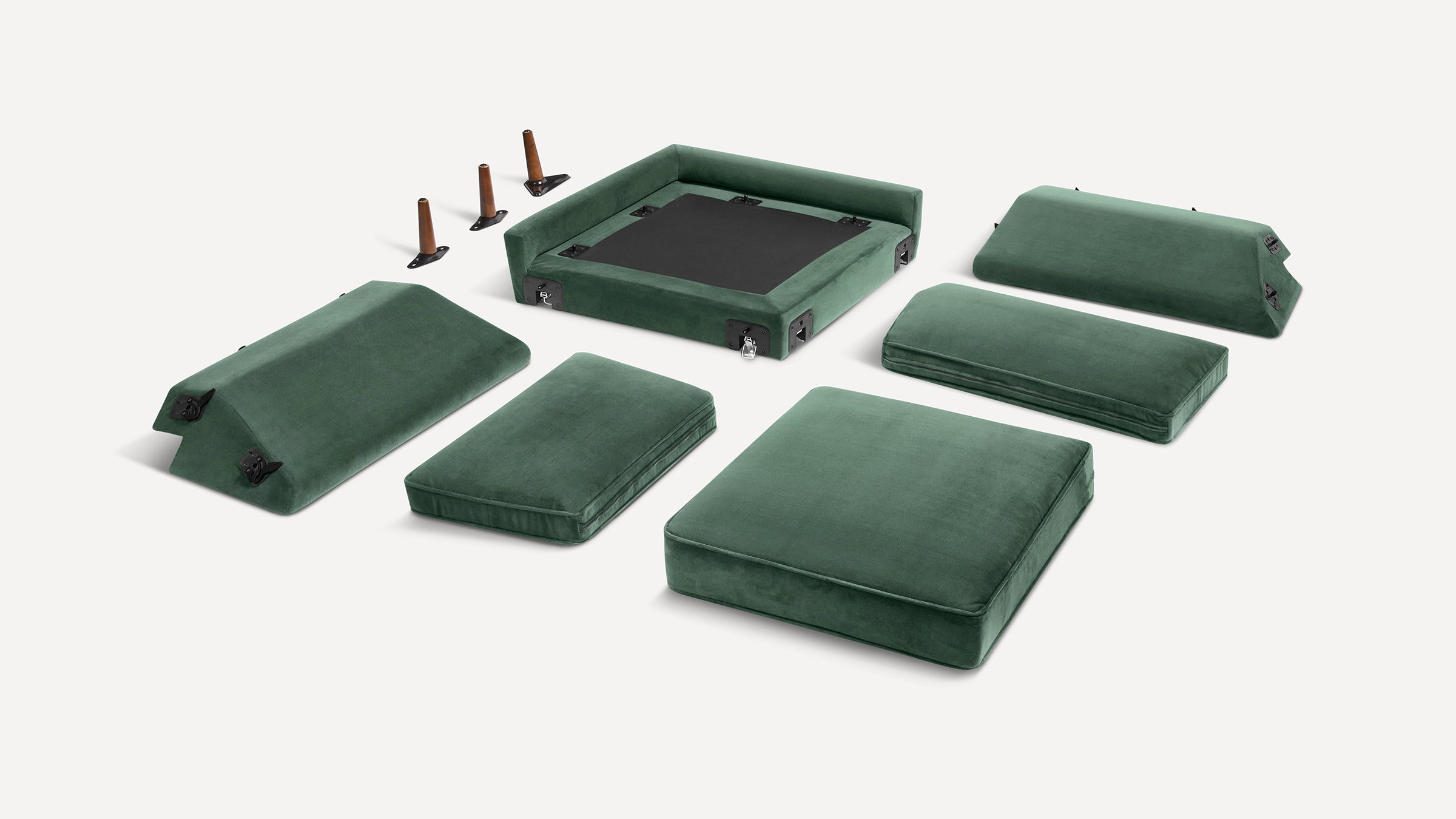 Disassembled green velvet sofa cushions, frame components, and four wooden legs arranged on a white background.