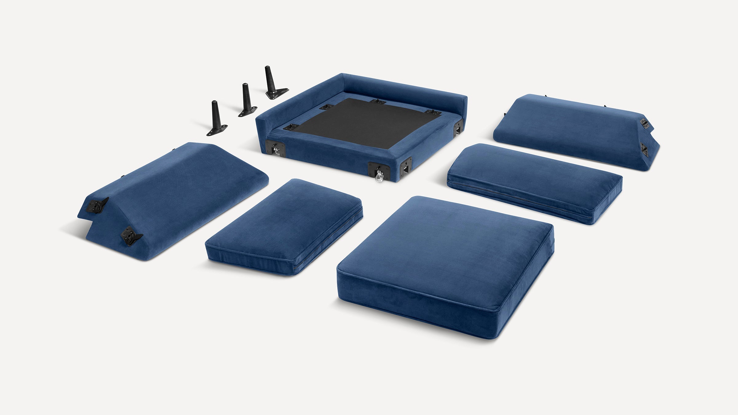 Disassembled blue velvet modular sofa cushions and parts laid out separately on a white background.