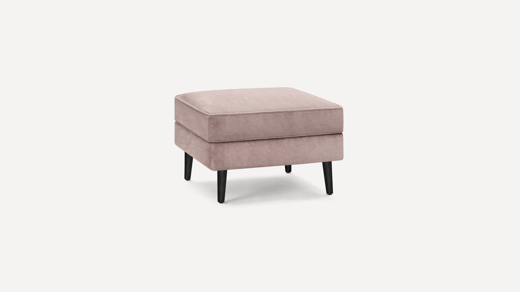 Square blush pink velvet ottoman with black tapered wooden legs, modern minimalist design.
