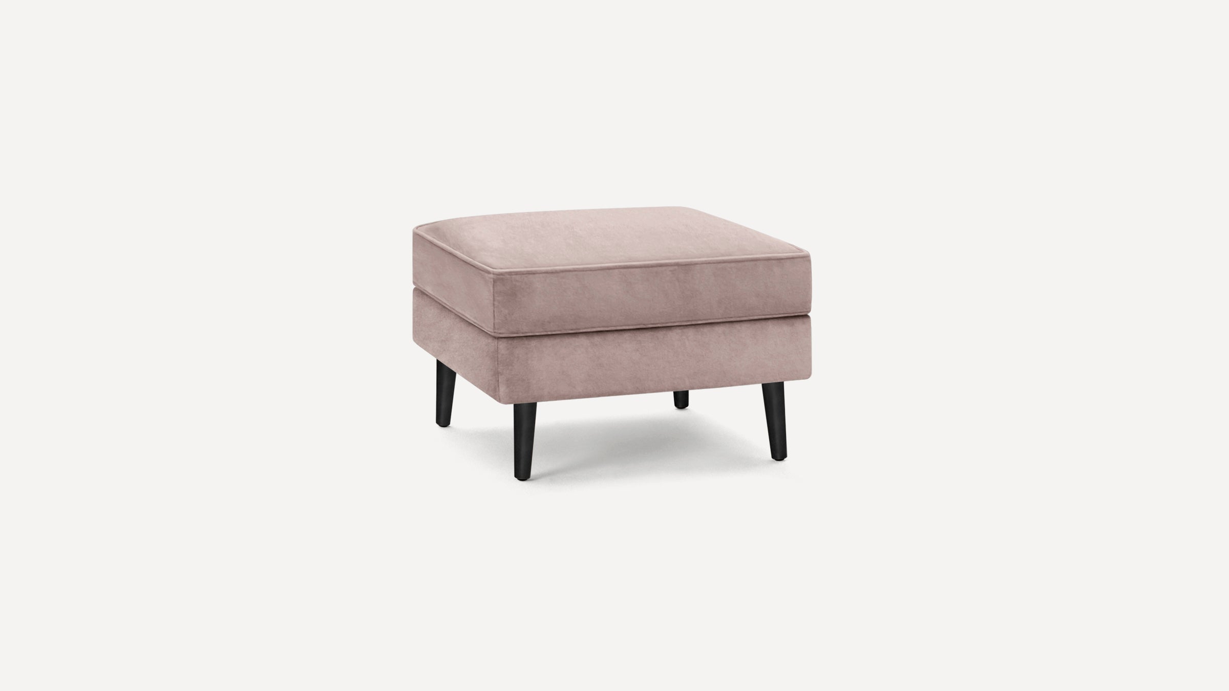 Square blush pink velvet ottoman with black tapered wooden legs, modern minimalist design.