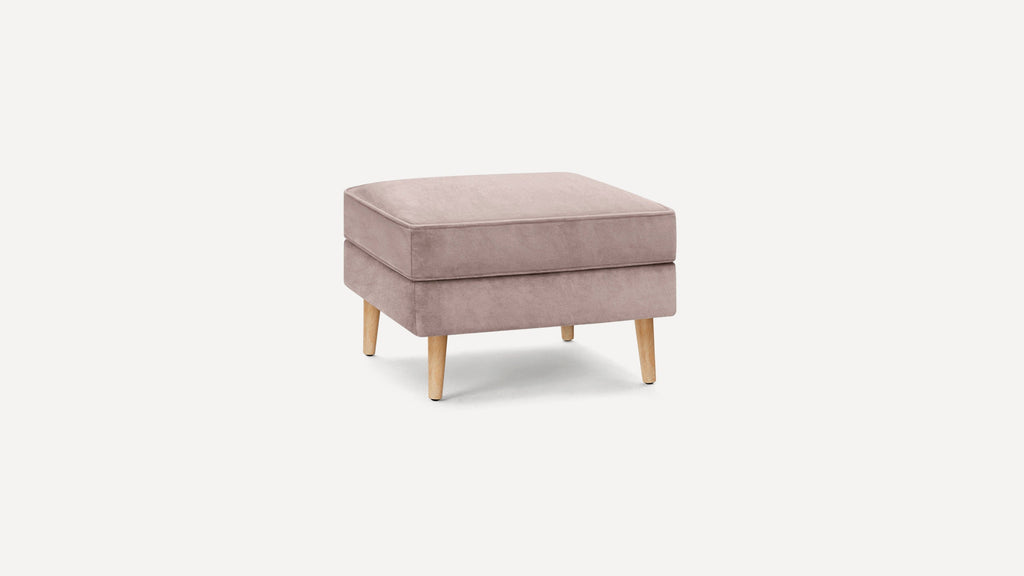 Square ottoman with soft dusty pink upholstery and four light wooden legs, set against a white background.