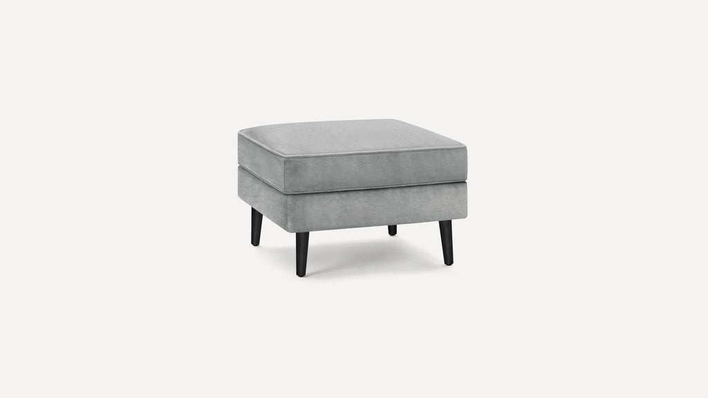 Square gray upholstered ottoman with black tapered wooden legs, featuring a cushioned top and modern design.