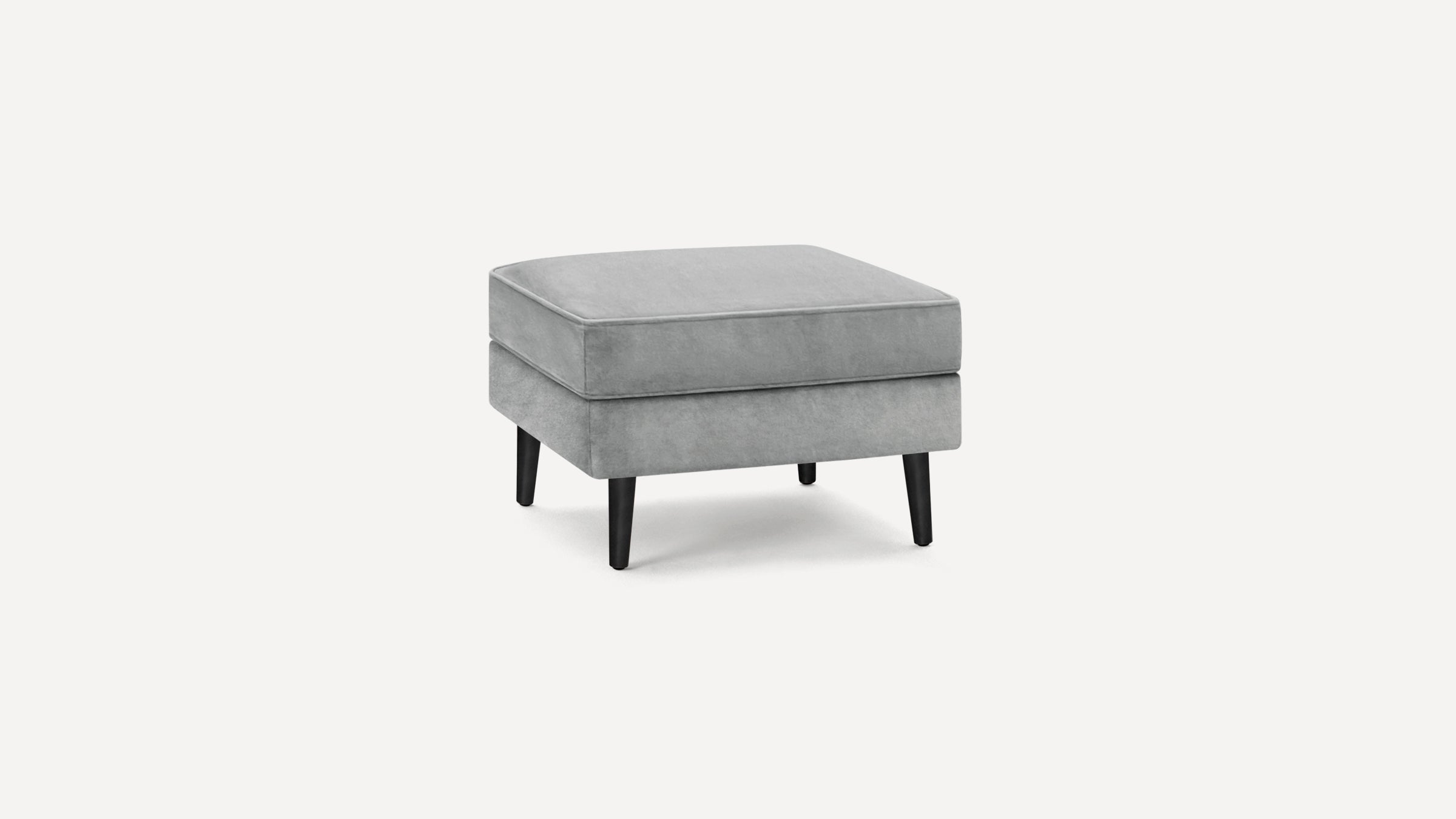 Square gray upholstered ottoman with black tapered wooden legs, featuring a cushioned top and modern design.