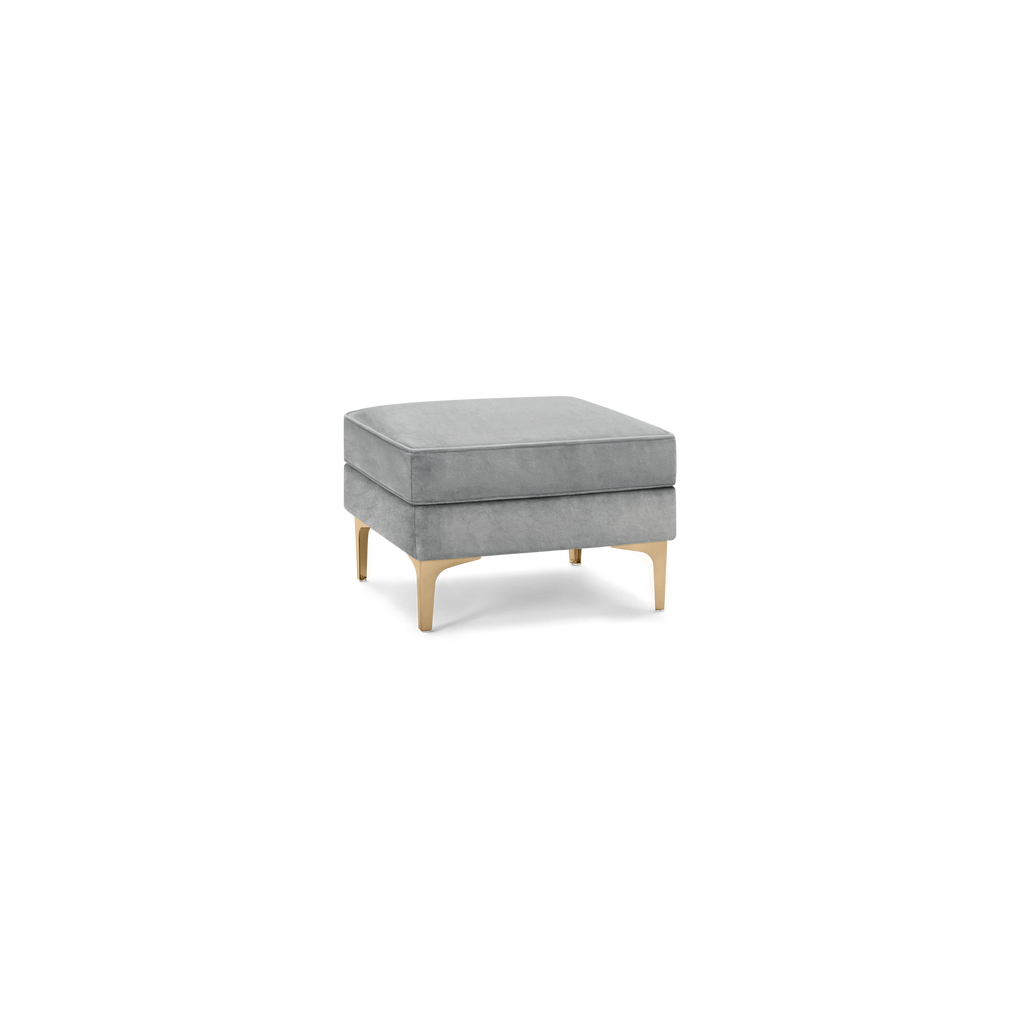 modern gray velvet ottoman with gold metal legs and a square cushion on a black background