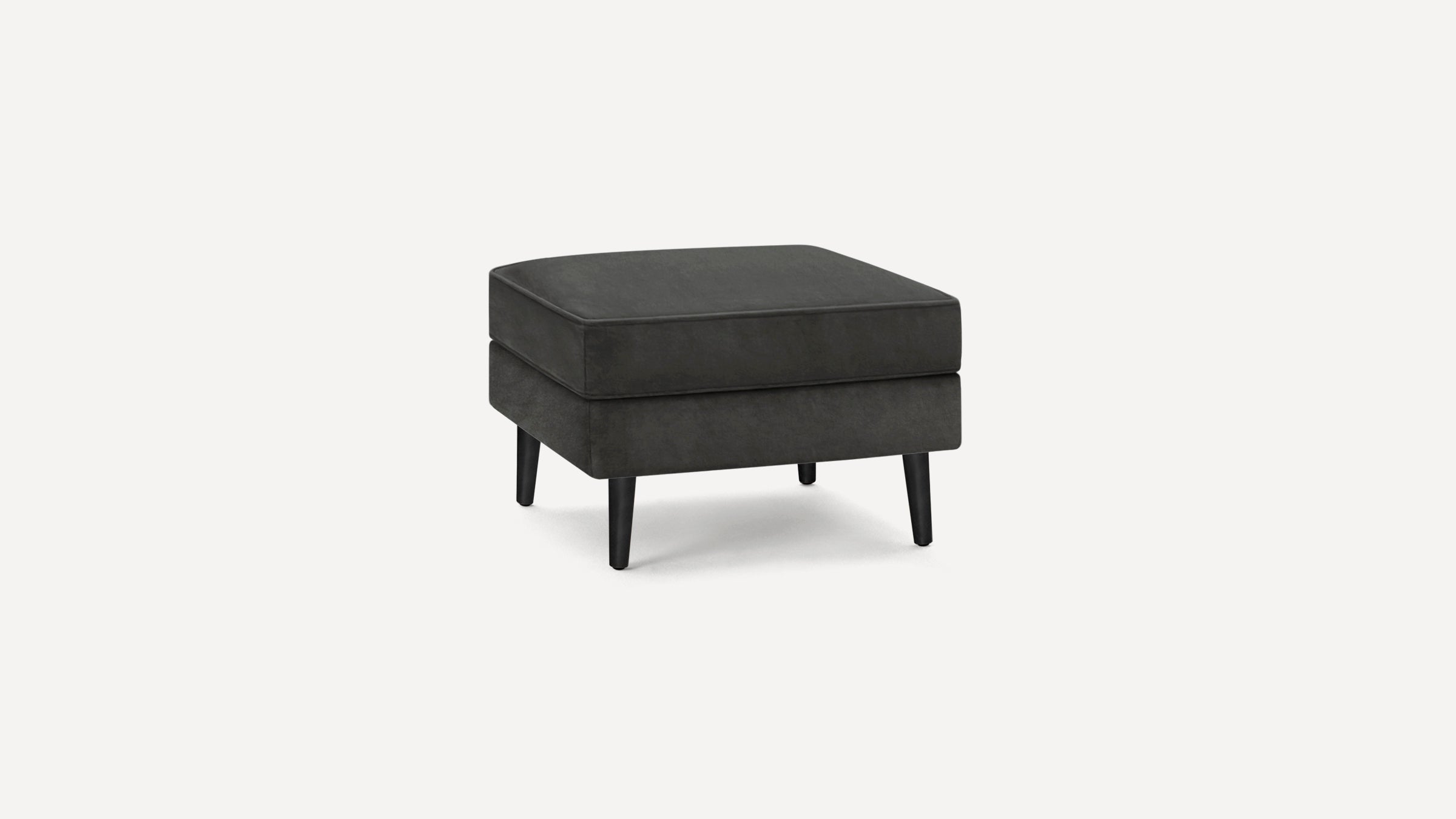 Dark gray upholstered square ottoman with cushioned top and four tapered black wooden legs on a white background.