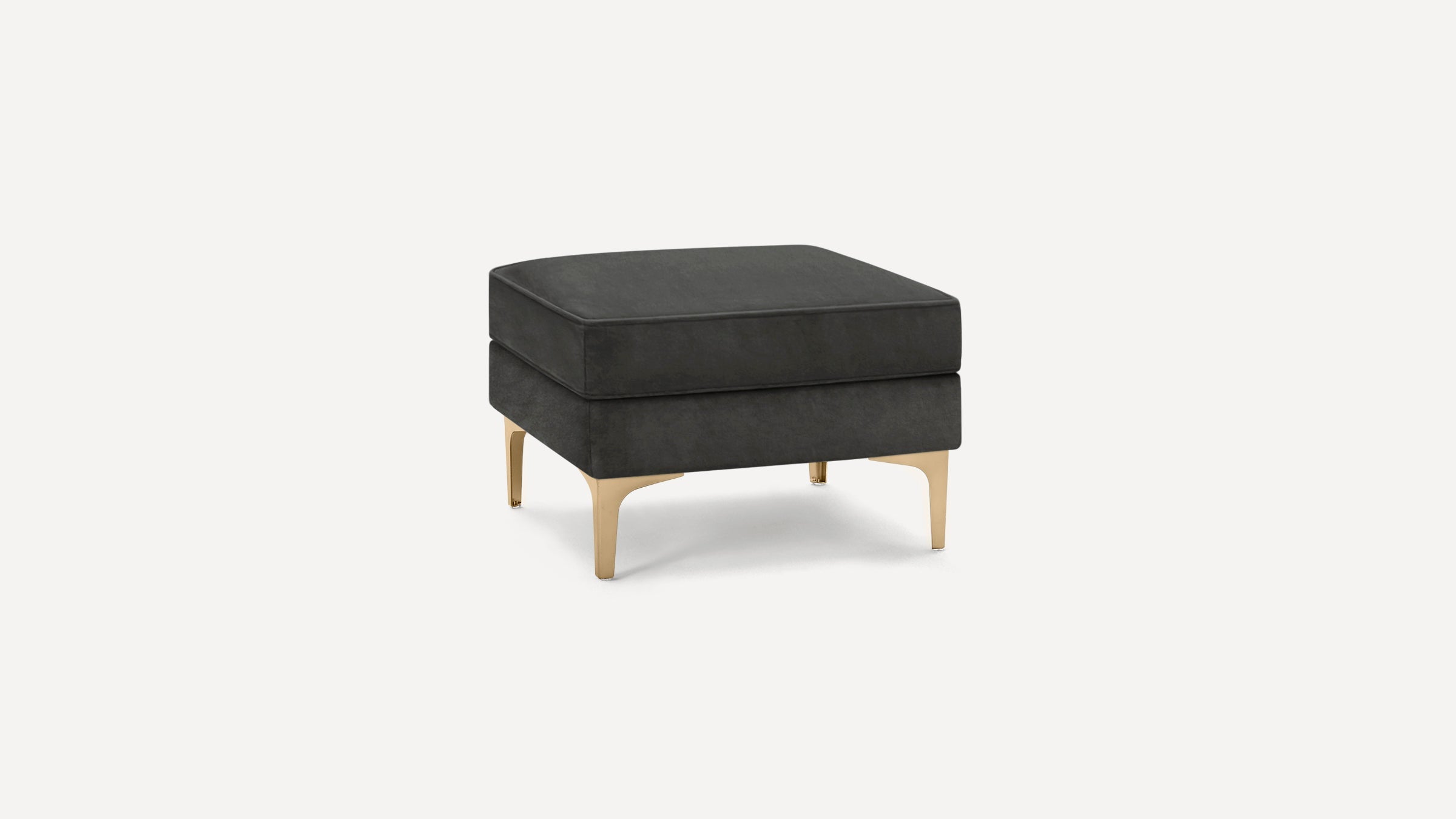 Square dark gray upholstered ottoman with cushioned top and gold metallic angled legs on white background.