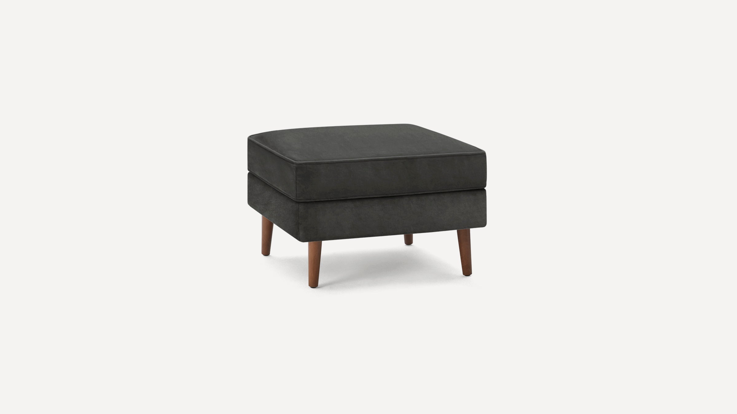 Square dark gray upholstered ottoman with four tapered wooden legs on a plain white background.