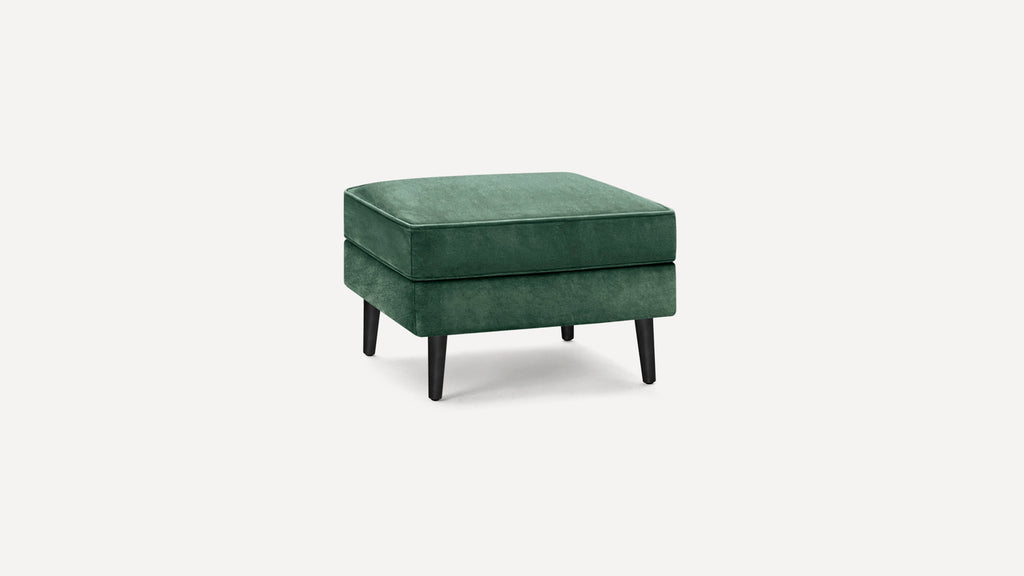 Square green velvet ottoman with black tapered wooden legs on white background.
