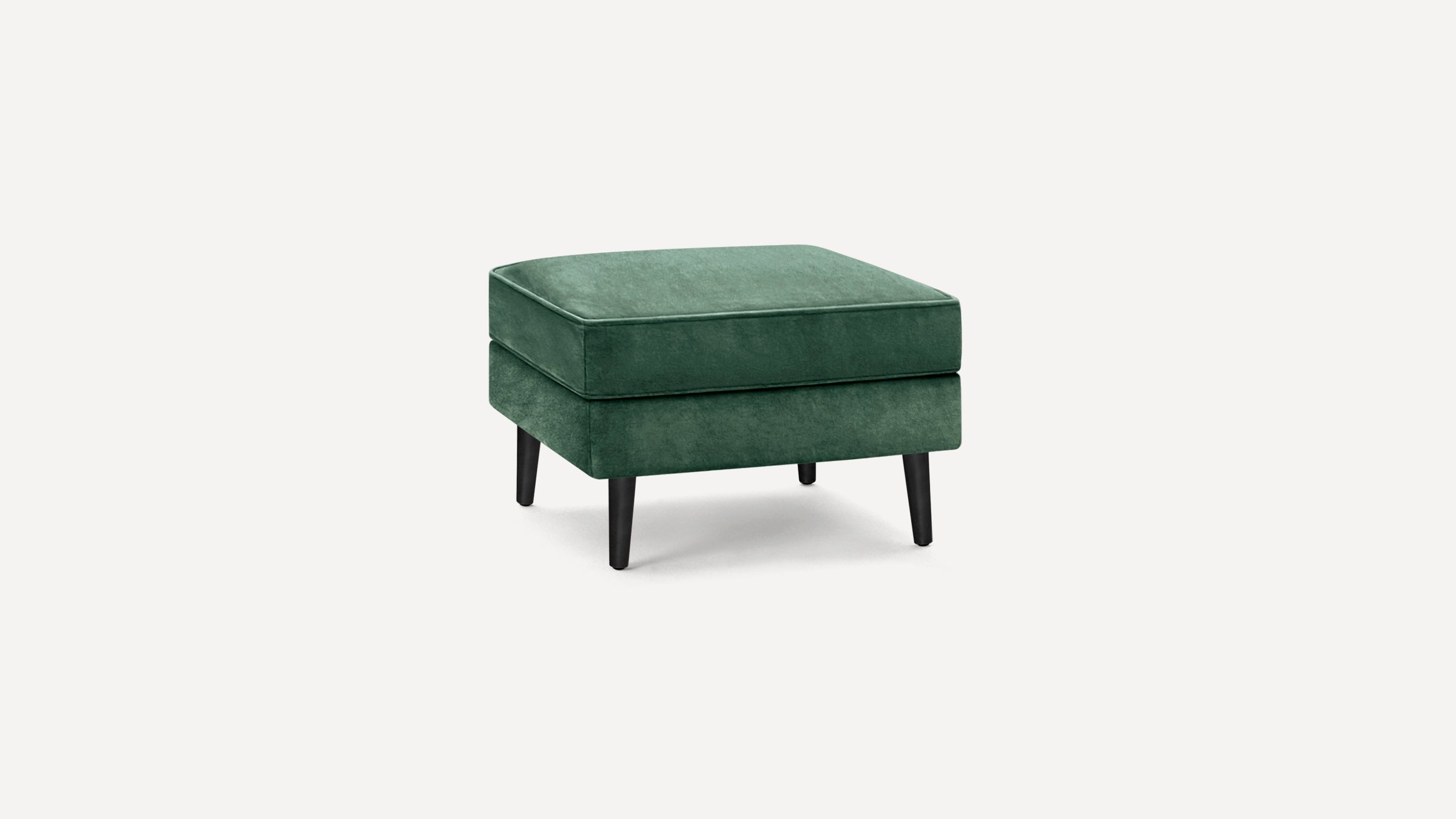 Square green velvet ottoman with black tapered wooden legs on white background.