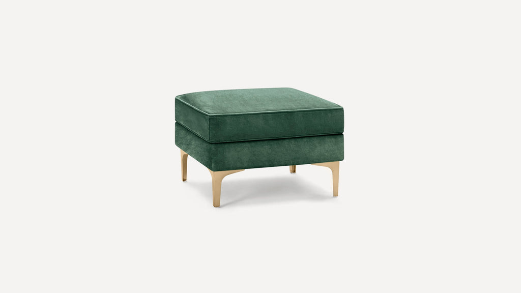 Square, green velvet ottoman with cushioned top and gold-colored metal legs on white background.