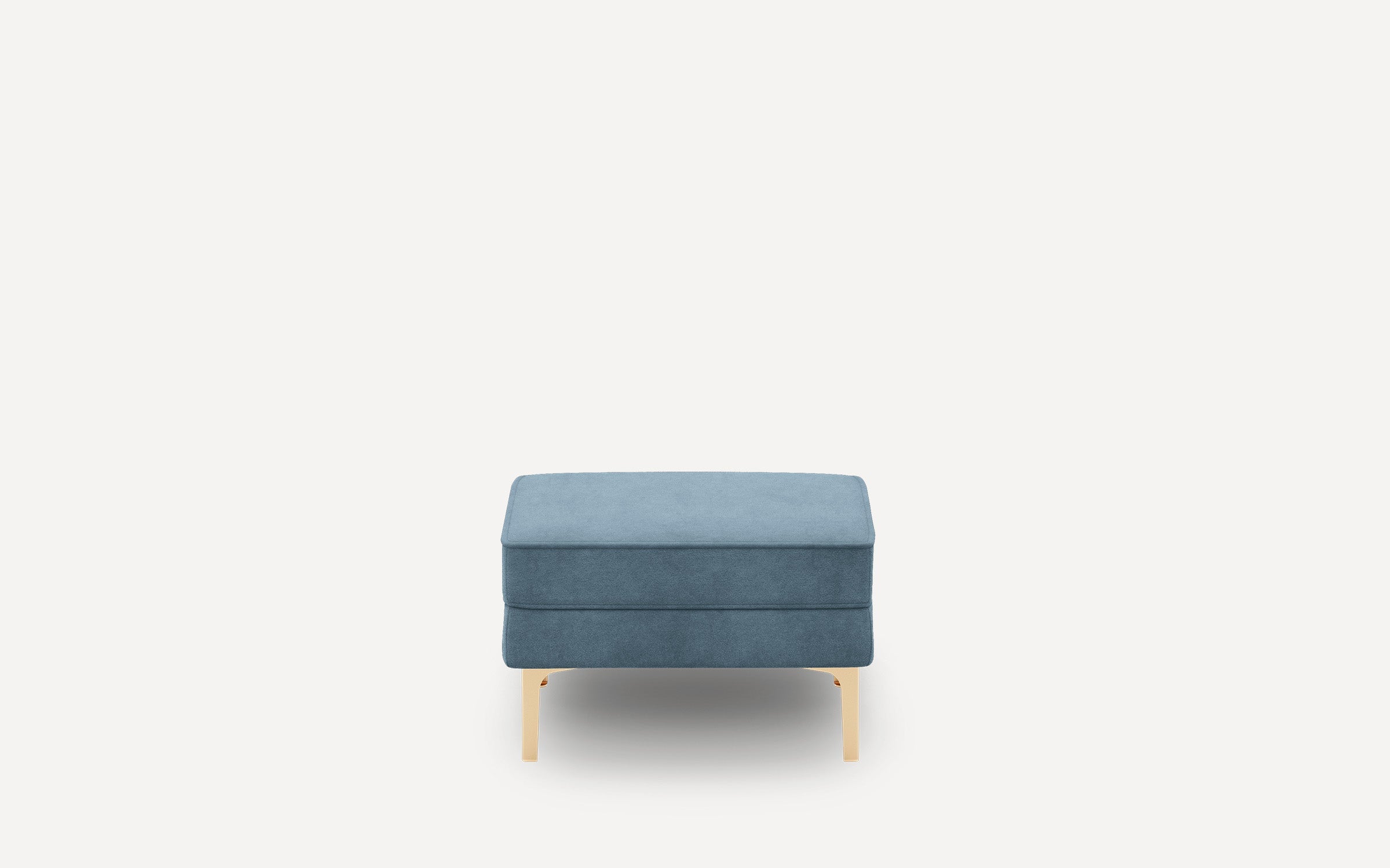Rectangular blue upholstered ottoman with smooth fabric, gold-toned metal legs, and minimalist modern design on a white background.