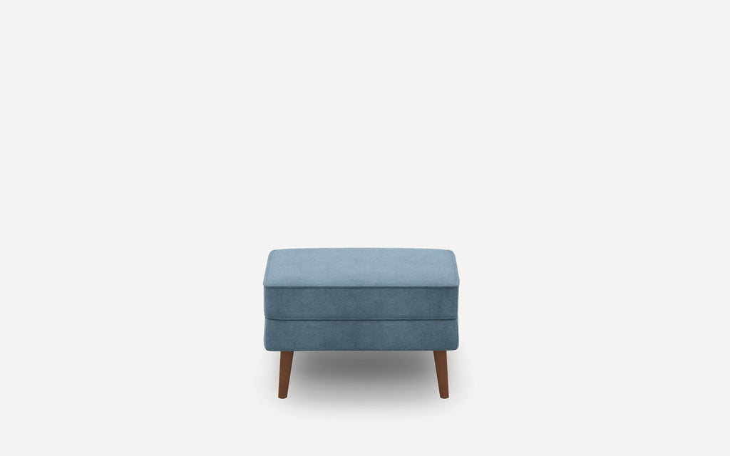 Small rectangular blue ottoman with soft fabric upholstery and four wooden tapered legs, shown against a white background.