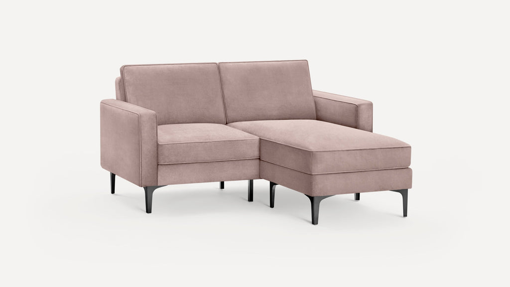 Modern blush pink upholstered sectional sofa with clean lines, slim black metal legs, and chaise lounge on the right side.