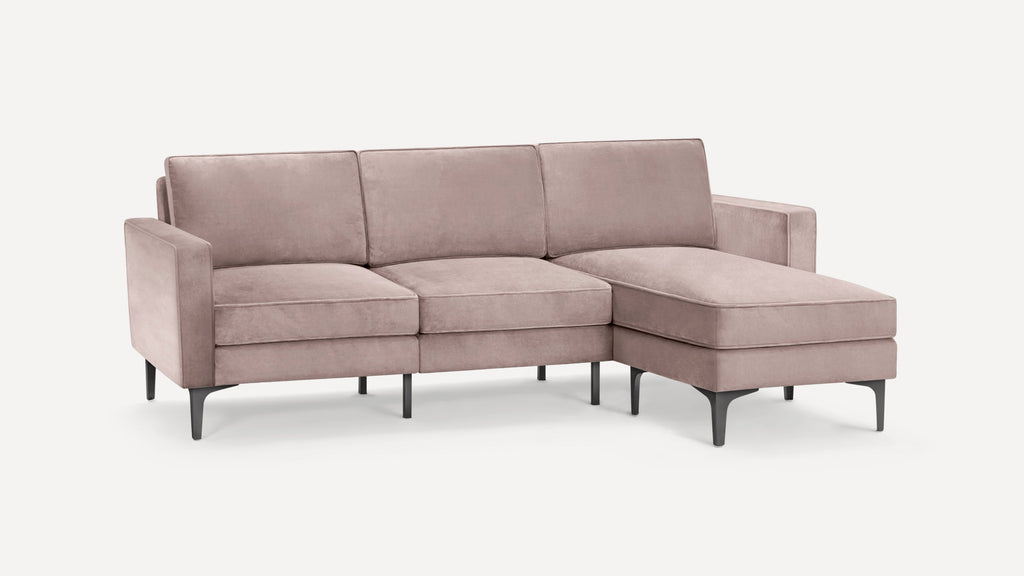 Modern light pink velvet sectional sofa with metal legs, featuring three seat cushions and a chaise on the right side.