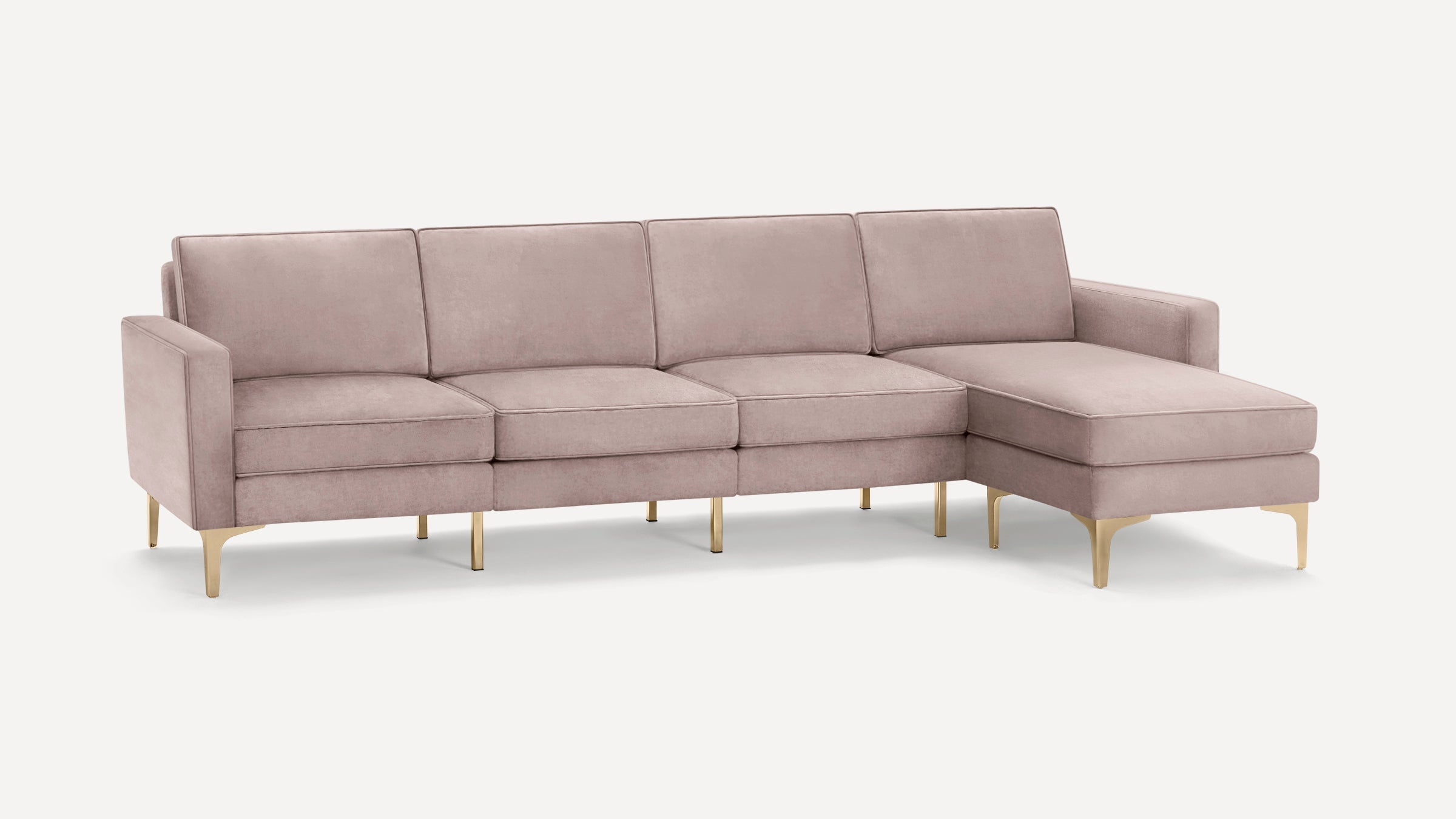 Modern sectional sofa in soft pink velvet upholstery with gold metal legs and chaise lounge on the right side.