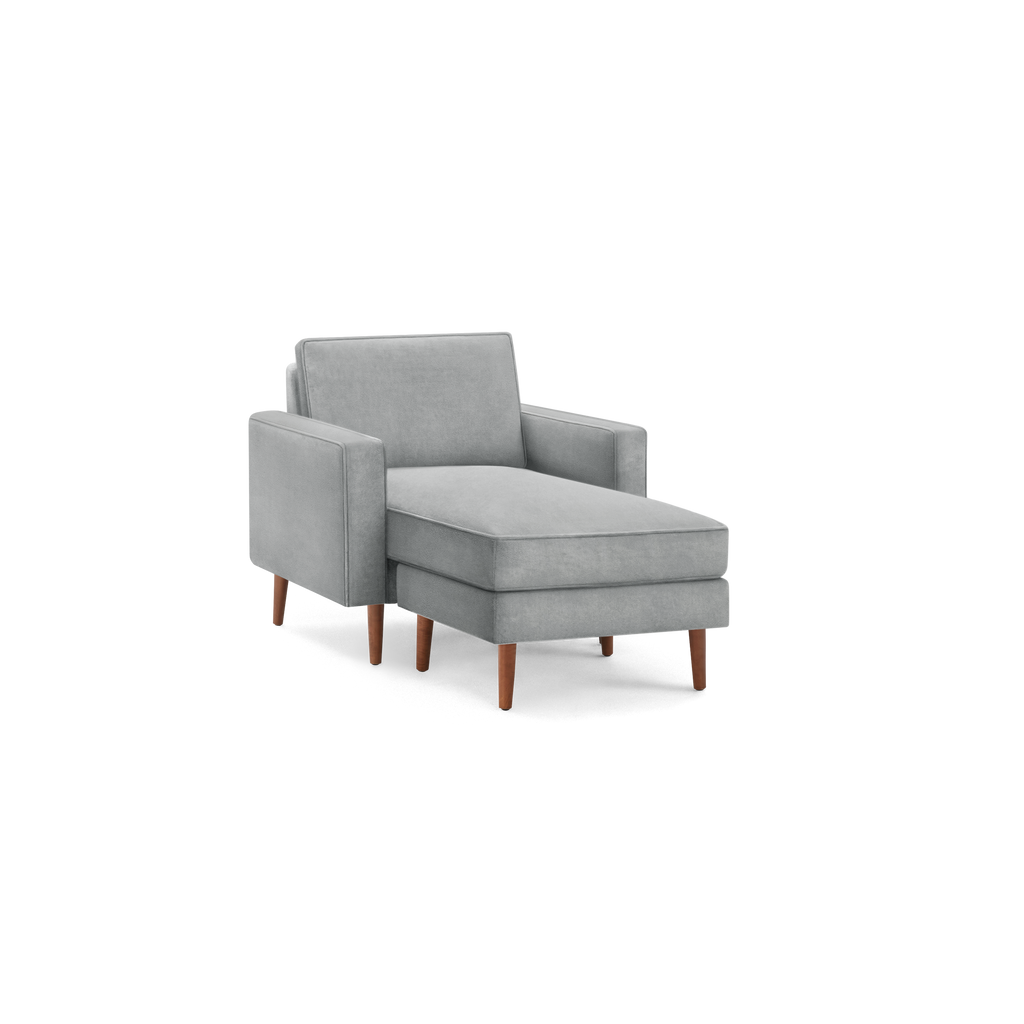 modern light gray upholstered armchair with wooden legs and a matching ottoman on a black background