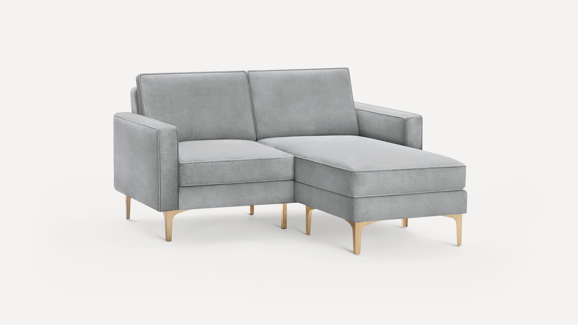 Light gray velvet sectional sofa with chaise lounge and gold metal legs on a plain white background.