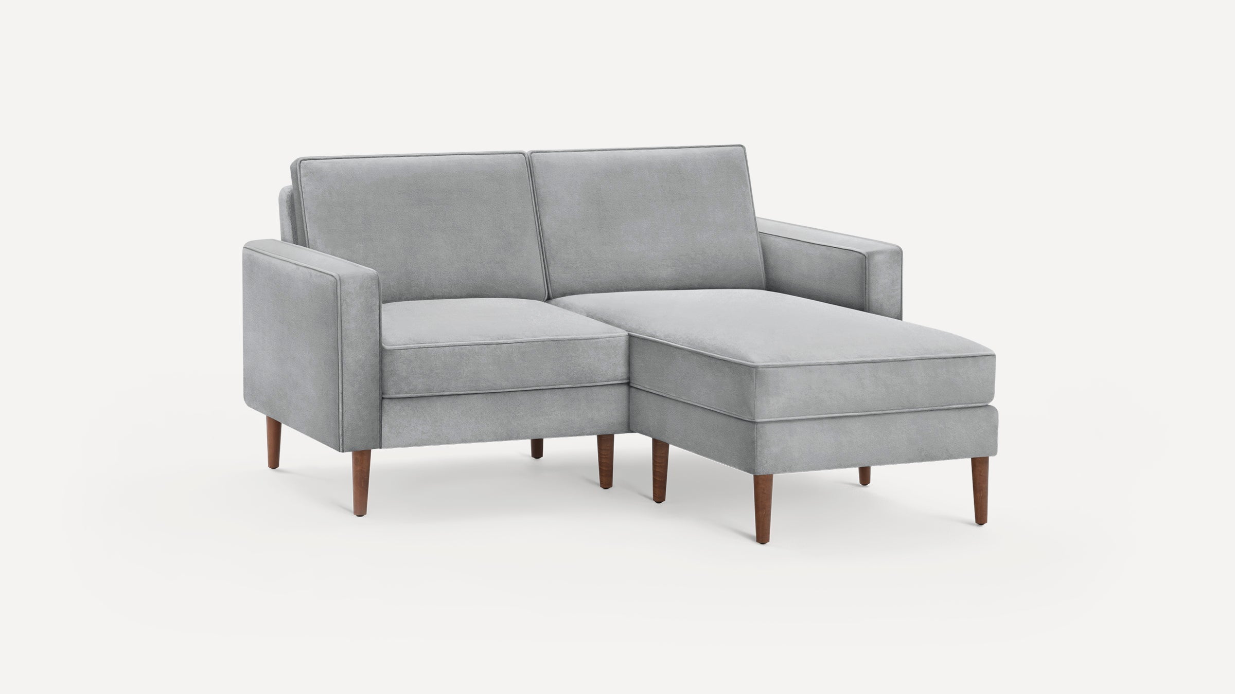 Light gray upholstered sectional sofa with right chaise, clean lines, and mid-century wooden legs on white background.