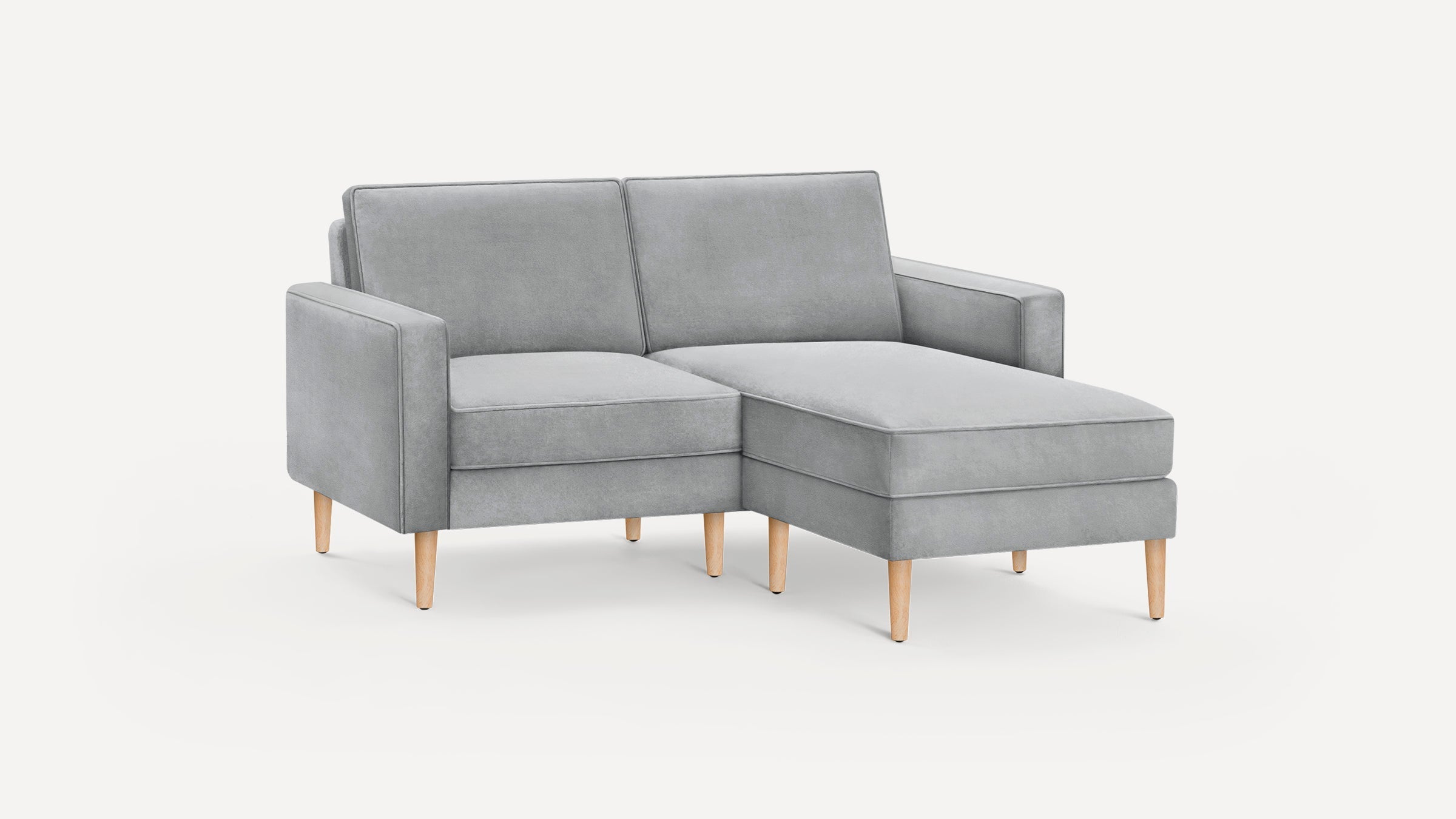 Light gray fabric sectional sofa with wooden legs and a chaise lounge on the right side, minimalist modern design.