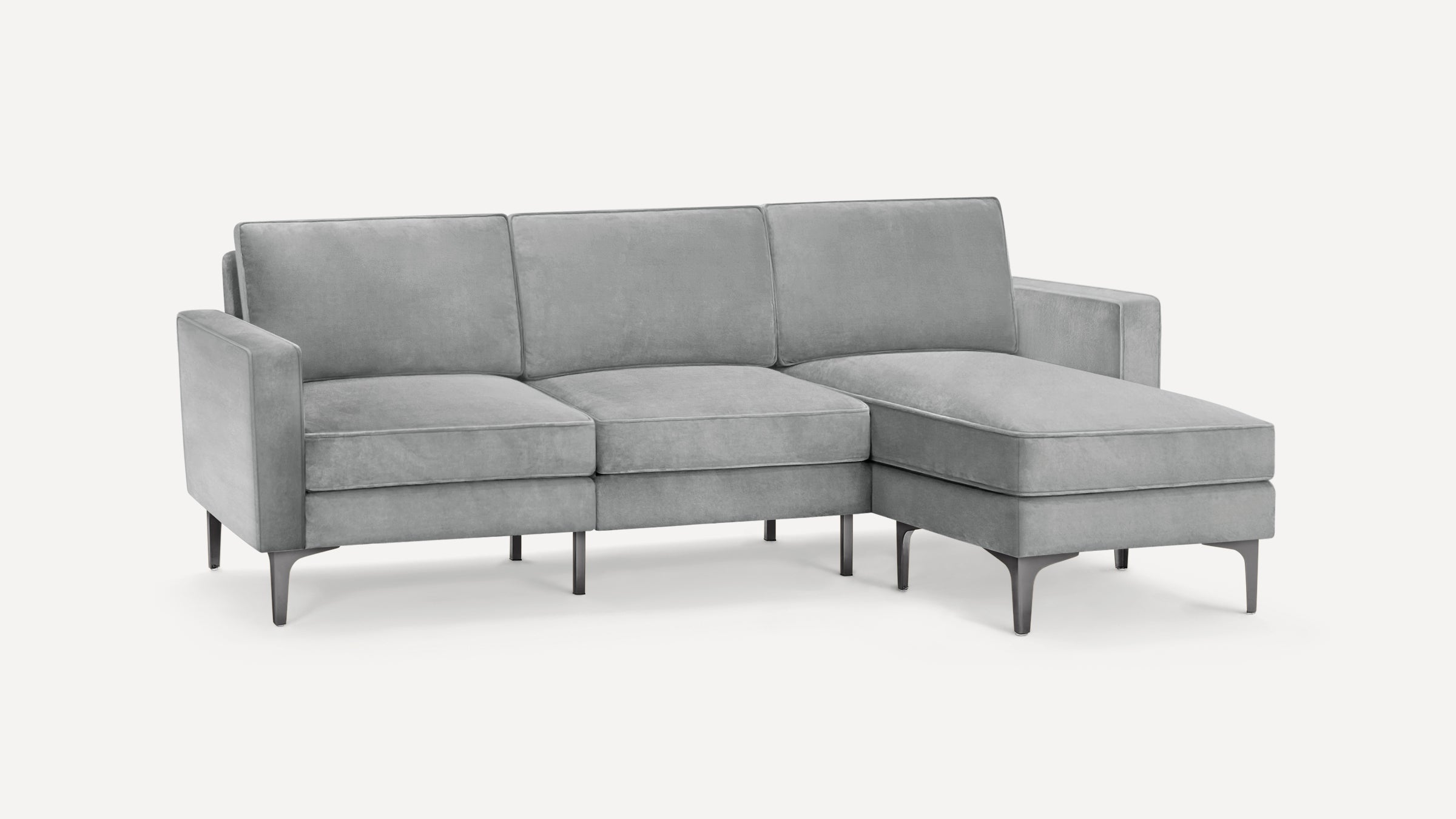 Modern light gray velvet sectional sofa with clean lines, slim metal legs, and a chaise lounge on the right side.