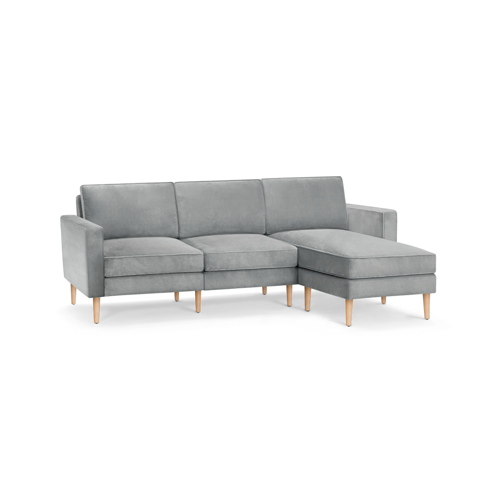 modern l - shaped sectional sofa with light gray fabric upholstery, tapered wooden legs, and clean lines on the backrests