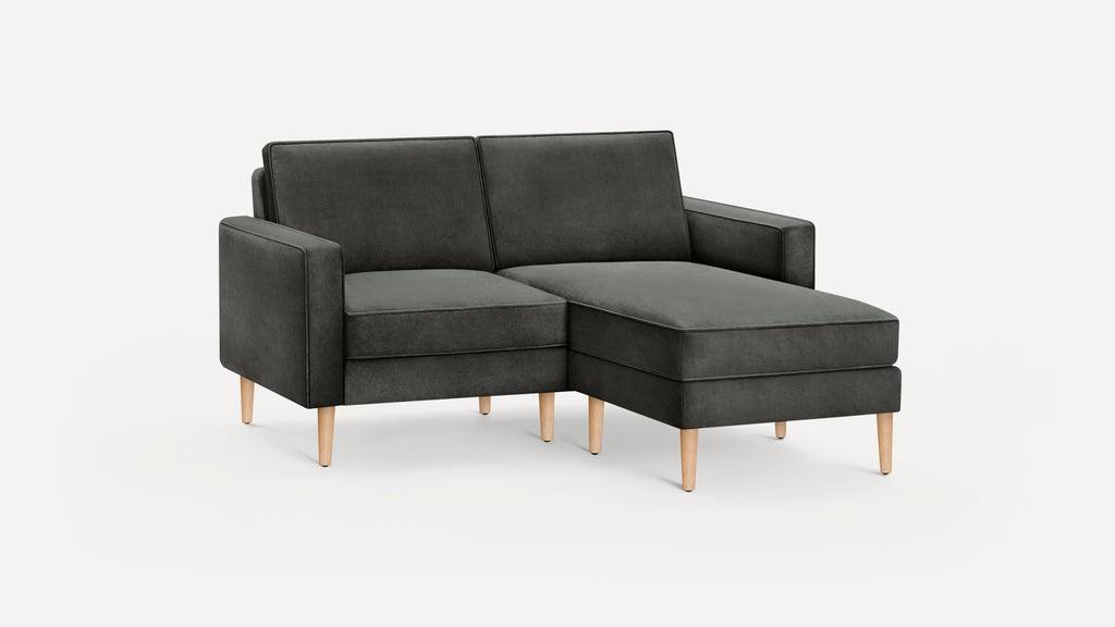 Modern dark gray upholstered chaise lounge sofa with wooden tapered legs, featuring clean lines and a minimalist design.