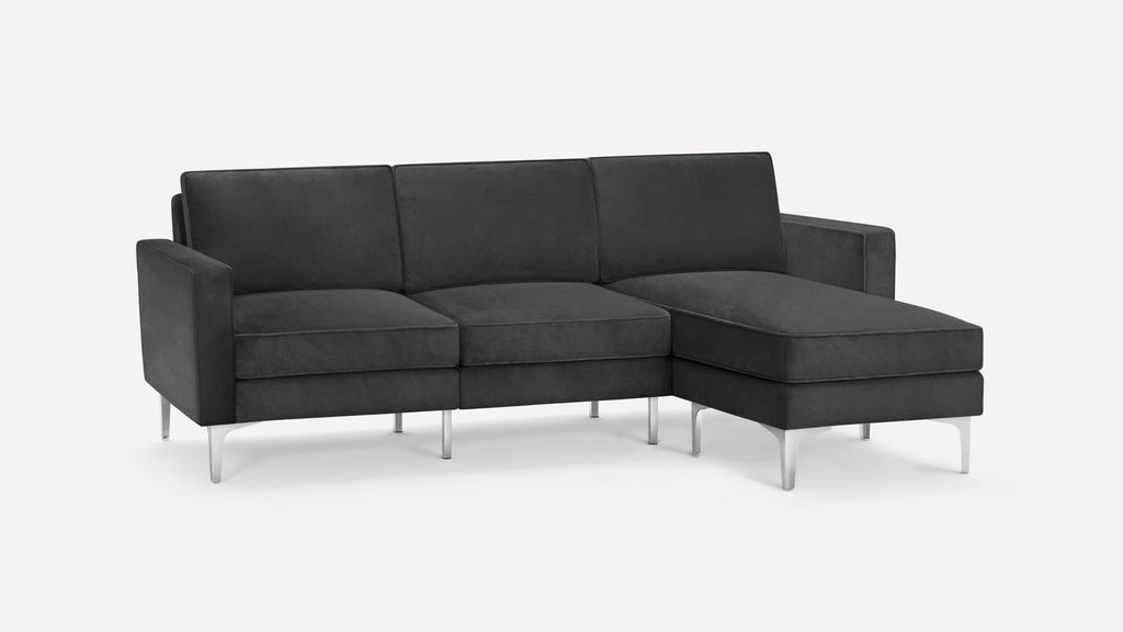 Dark gray modern sectional sofa with metal legs, three seat cushions, and a chaise lounge on the right side.