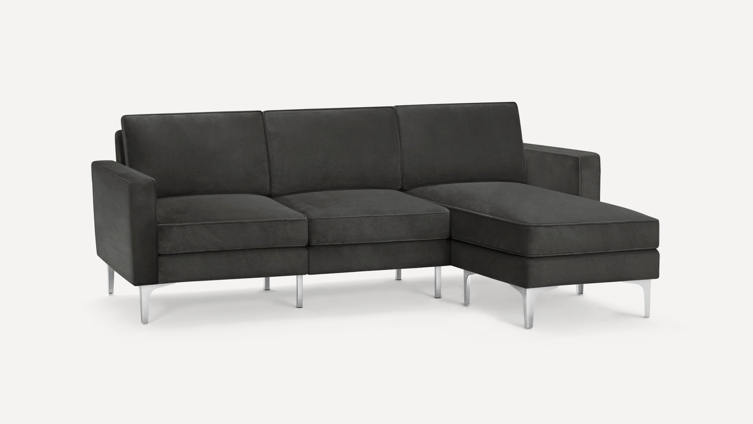 Dark gray modern sectional sofa with metal legs, three seat cushions, and a chaise lounge on the right side.