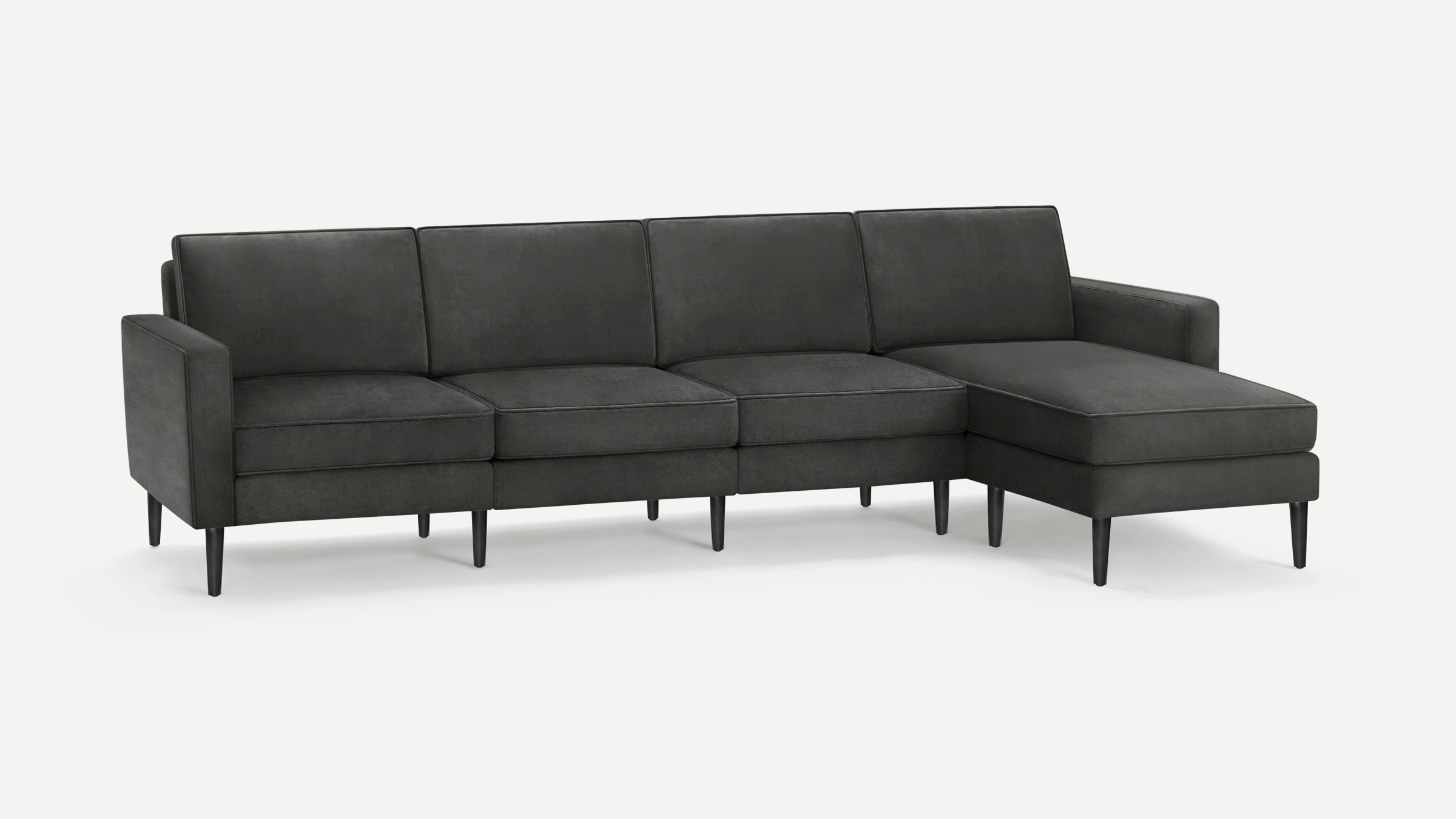 Dark gray modern sectional sofa with four seat cushions, straight arms, and sleek black tapered legs on white background.