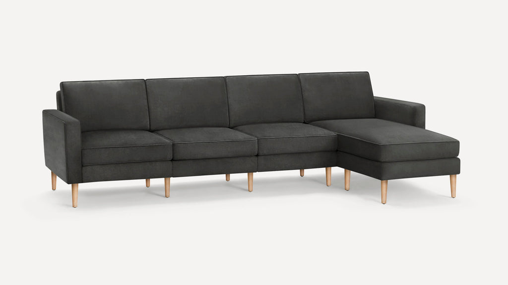 Modern dark gray sectional sofa with clean lines, wooden legs, and chaise lounge on the right side, against a plain white background.