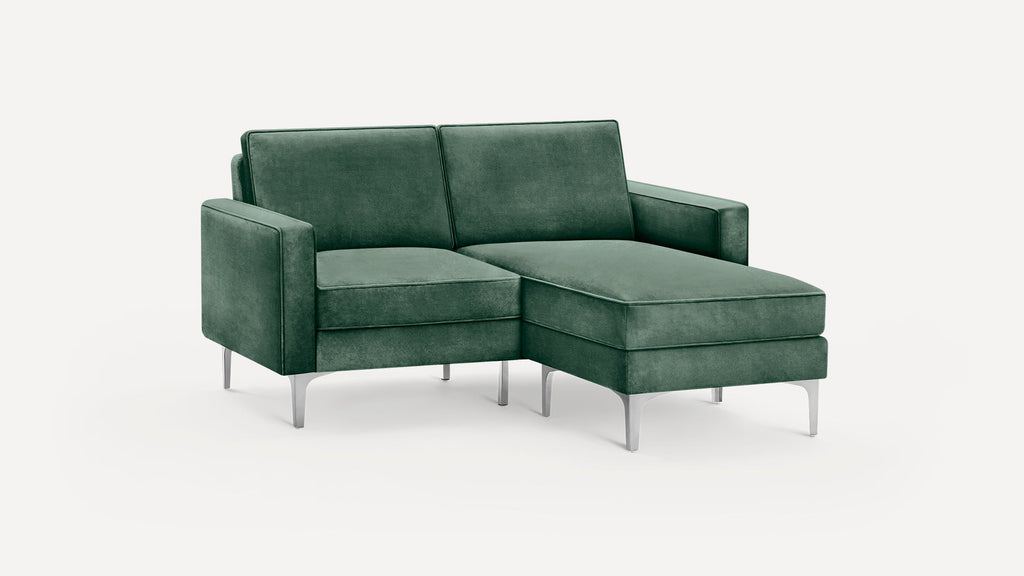 Modern green velvet sectional sofa with chaise lounge, clean lines, and slim silver metal legs on a white background.