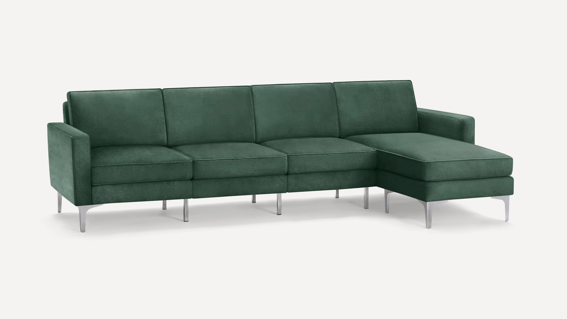 Modern sectional sofa with deep green velvet upholstery and sleek silver metal legs, featuring a chaise lounge on the right side.