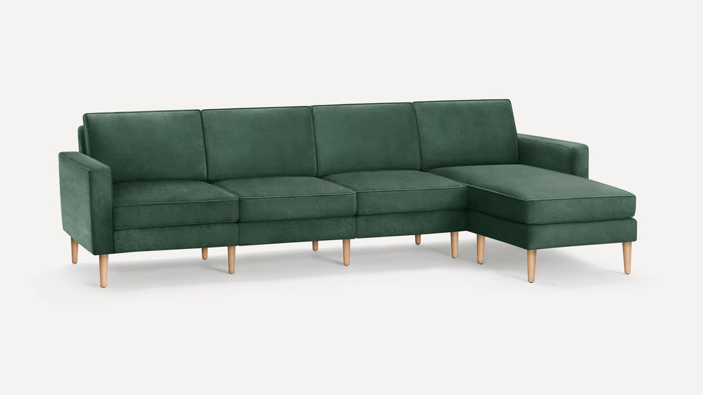 Modern green velvet sectional sofa with chaise lounge and wooden tapered legs on white background.