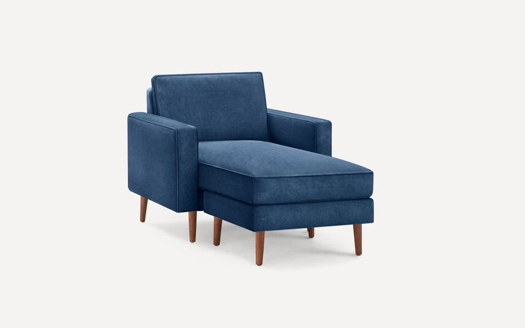 Modern blue velvet chaise lounge chair with wooden tapered legs and cushioned backrest and seat.