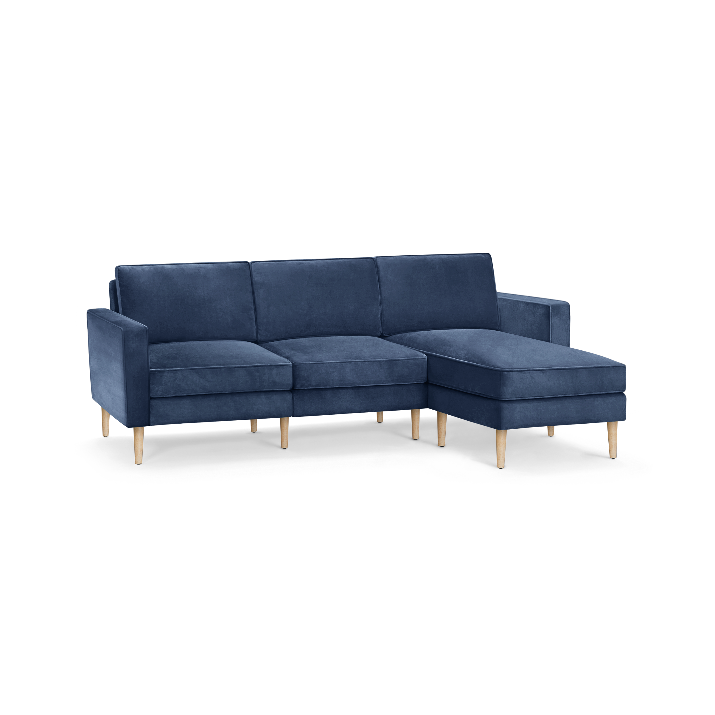 modern blue velvet sectional sofa with wooden legs and clean lines on the back, featuring a chaise lounge and matching ottoman