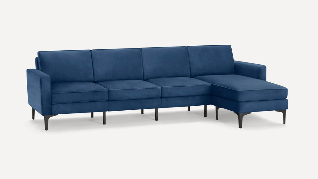 Modern sectional sofa in deep blue velvet with right chaise, slim black metal legs, and clean lines.