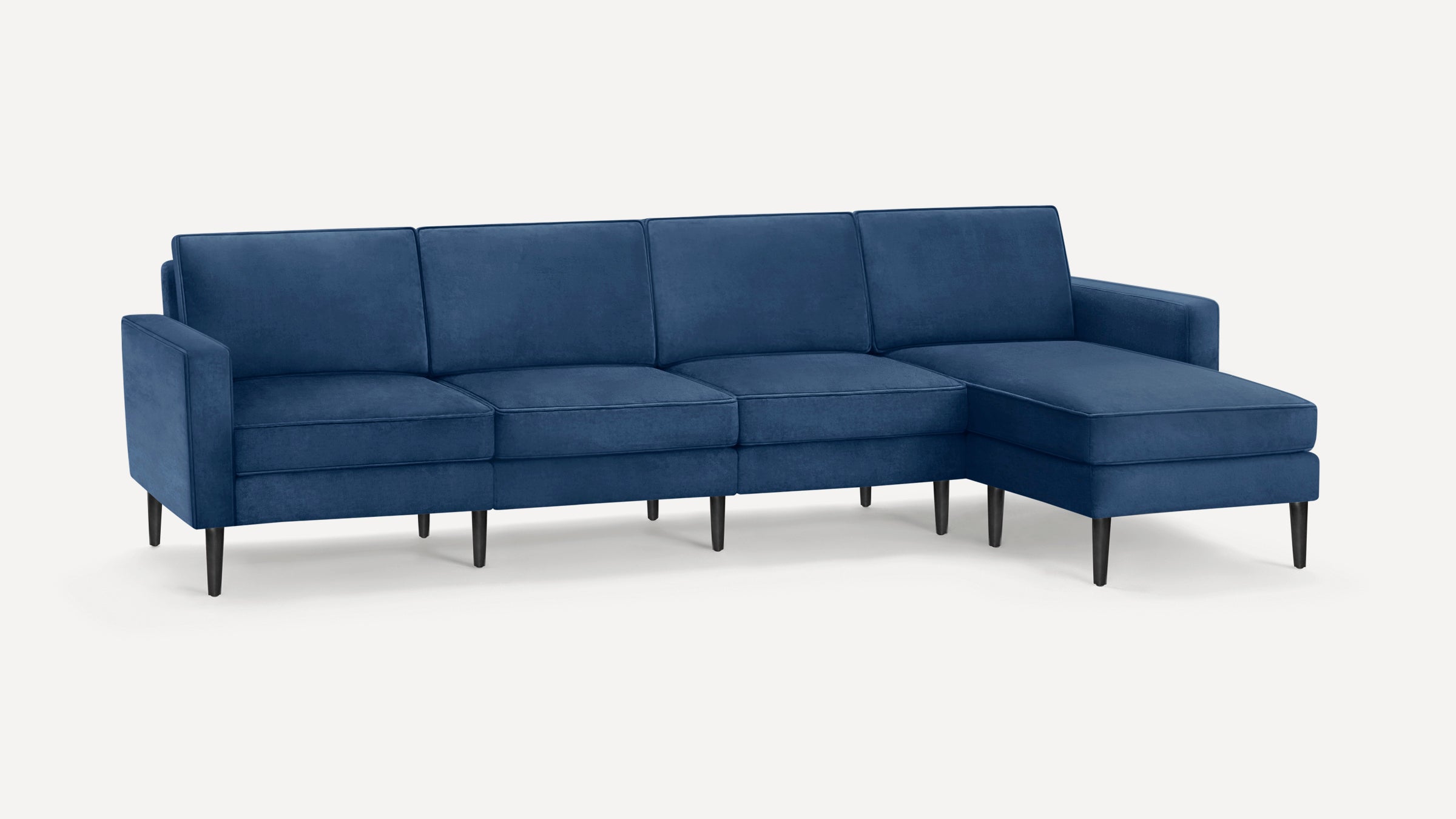 Modern blue velvet sectional sofa with clean lines, black tapered legs, and right-side chaise lounge on white background.