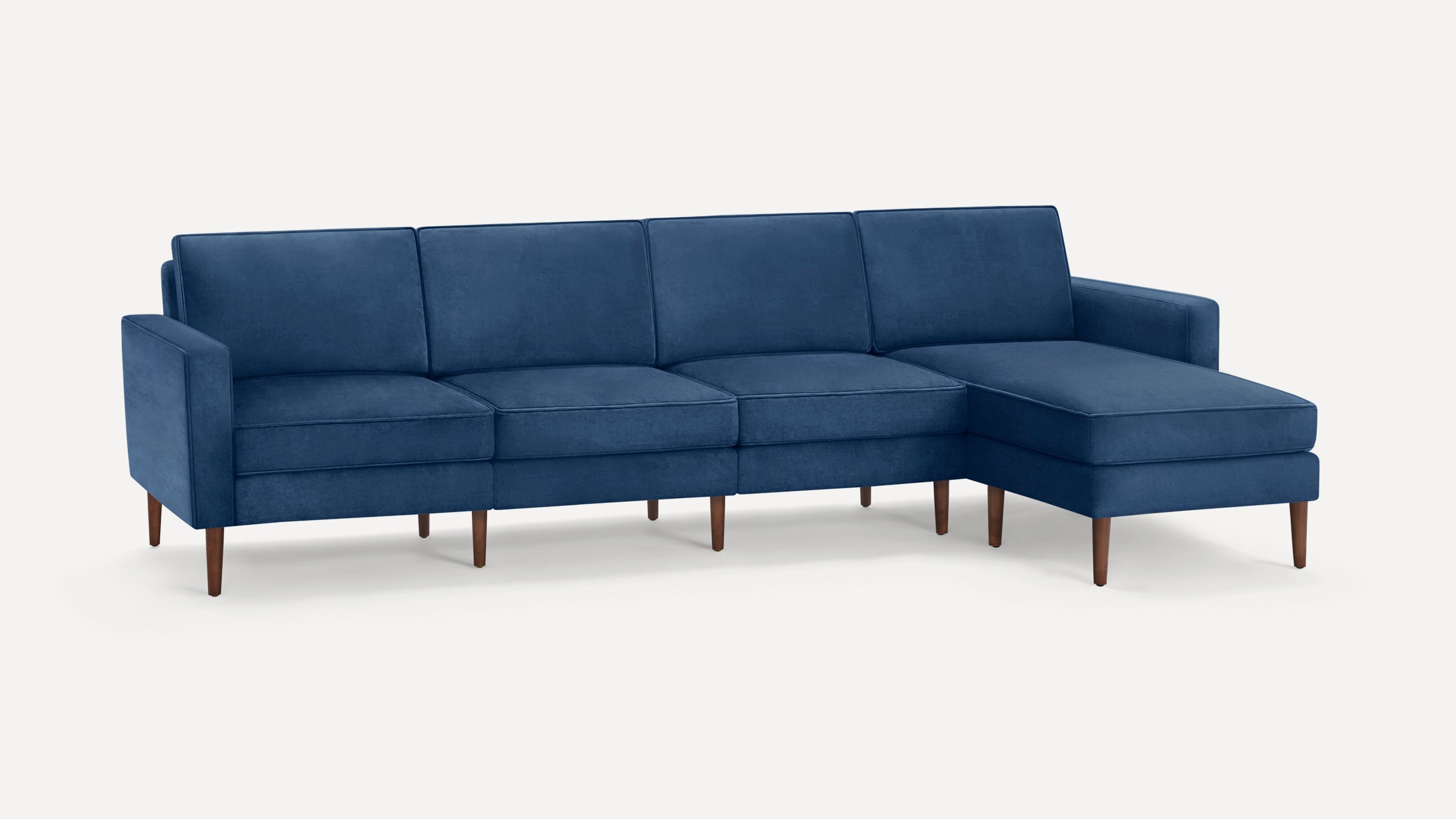Modern sectional sofa with deep blue upholstery, clean lines, and wooden tapered legs, featuring a chaise lounge on the right side.