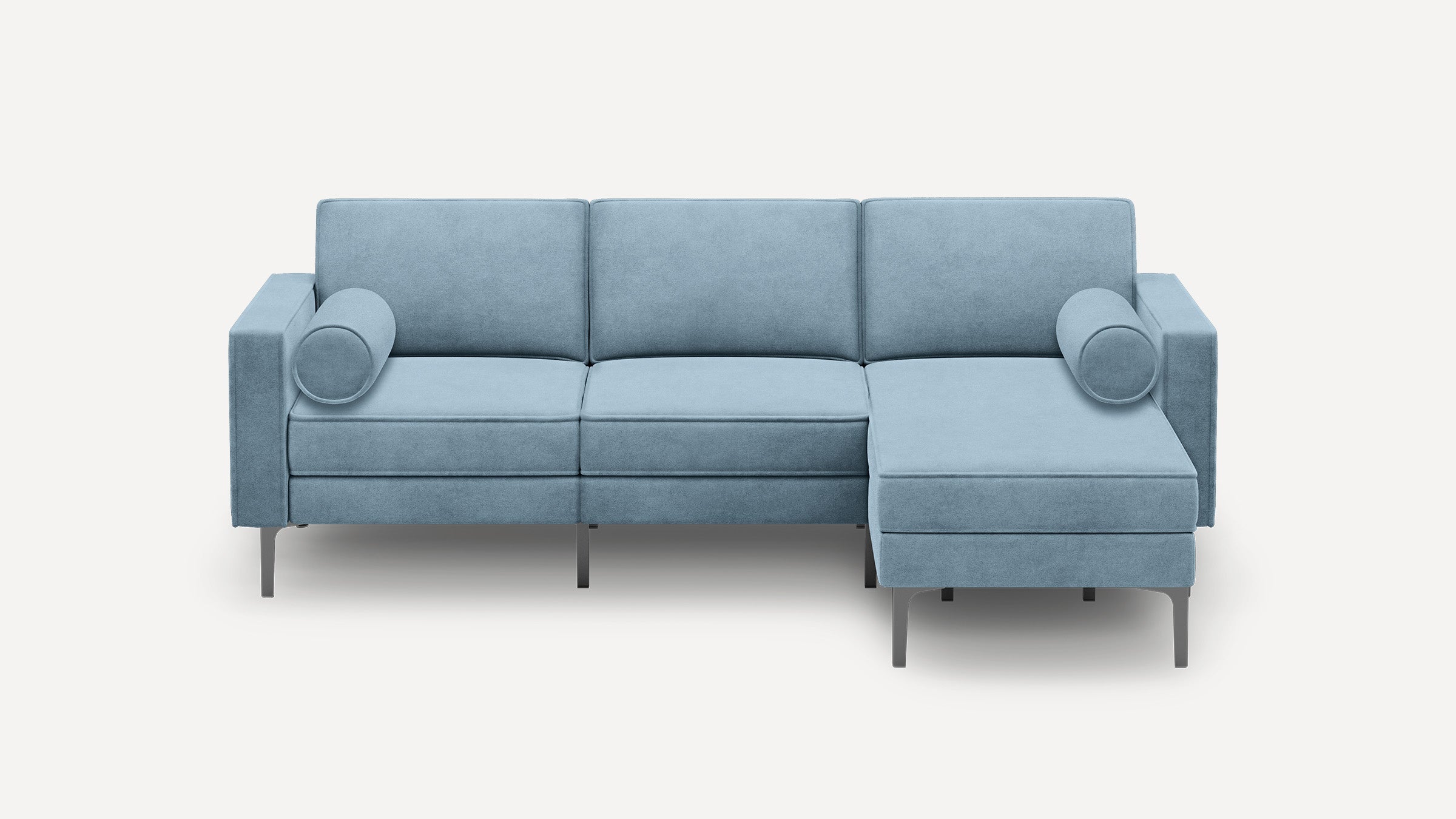 Light blue L-shaped sectional sofa with metal legs and two cylindrical bolster pillows, modern minimalist design.