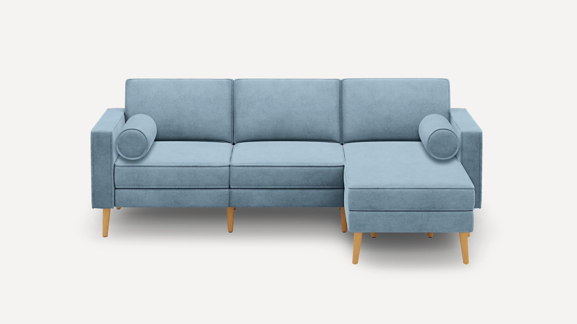 Light blue upholstered modern sectional sofa with wooden legs, featuring three seat cushions and two round bolster pillows.