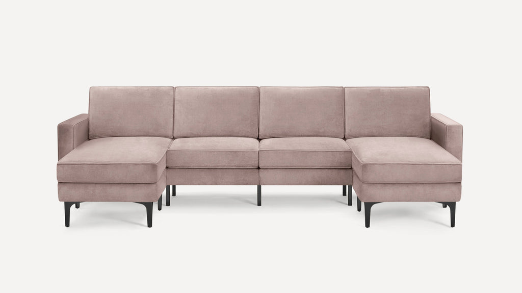 Modern blush pink velvet sectional sofa with black metal legs, featuring two chaise ends and three back cushions.
