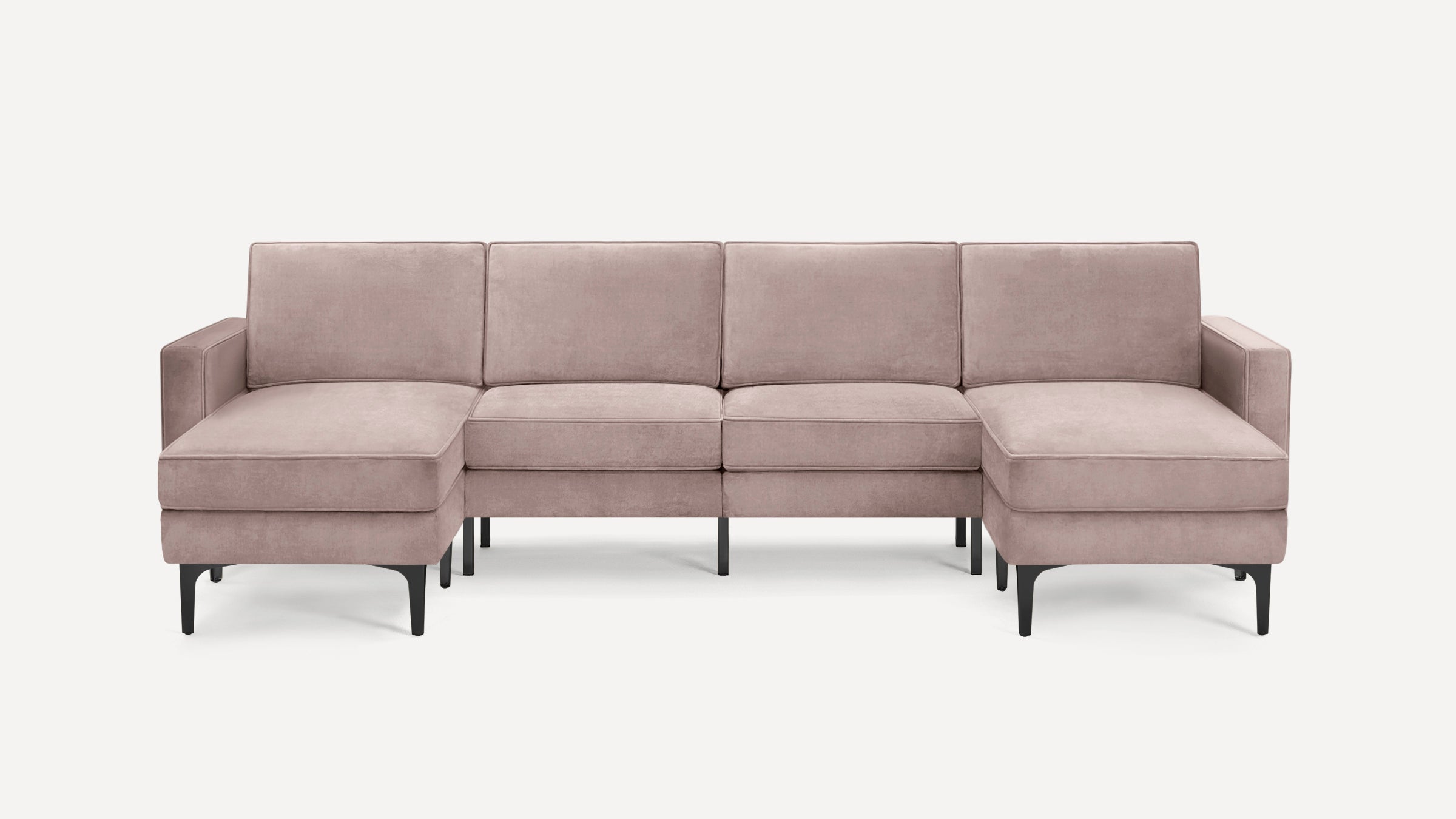 Modern blush pink velvet sectional sofa with black metal legs, featuring two chaise ends and three back cushions.